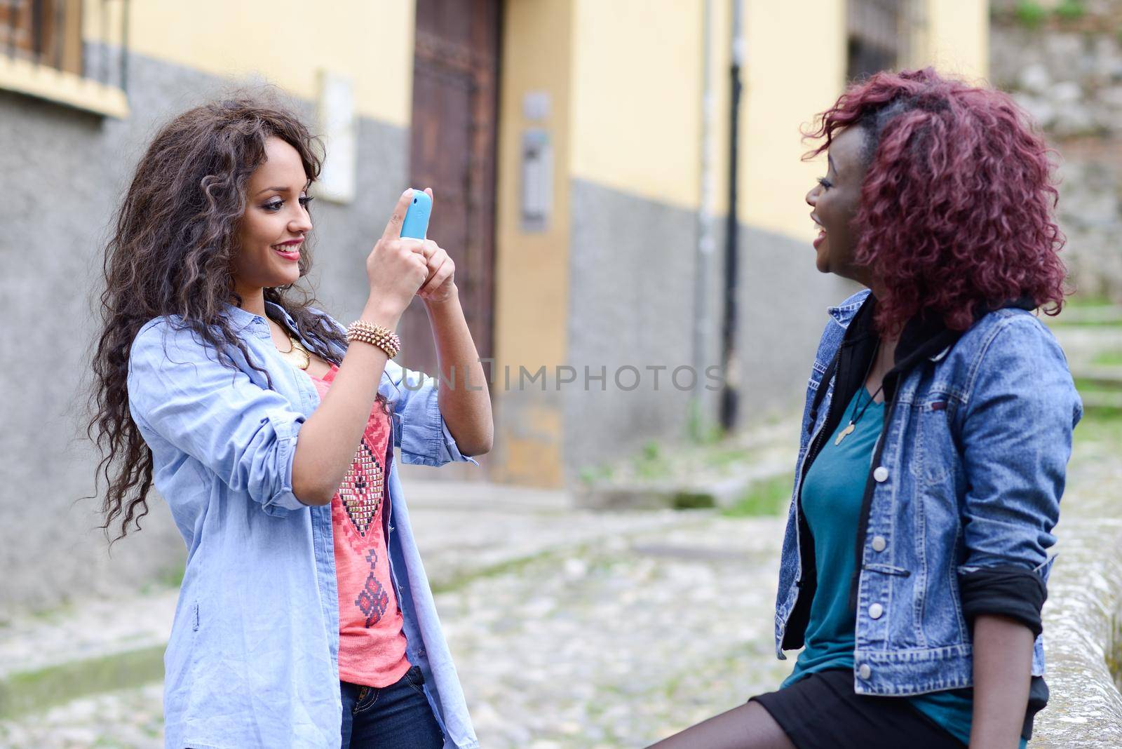 Happy young girls taking pictures of themselves through cellphone by javiindy