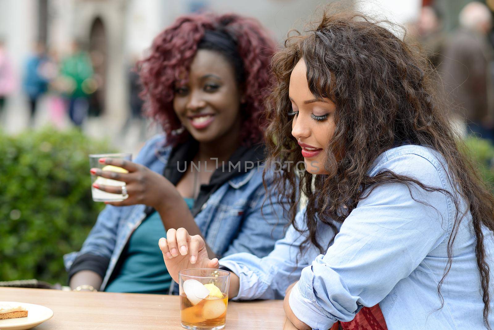 Portrait of two women taking a drink in a bar. Urban background by javiindy