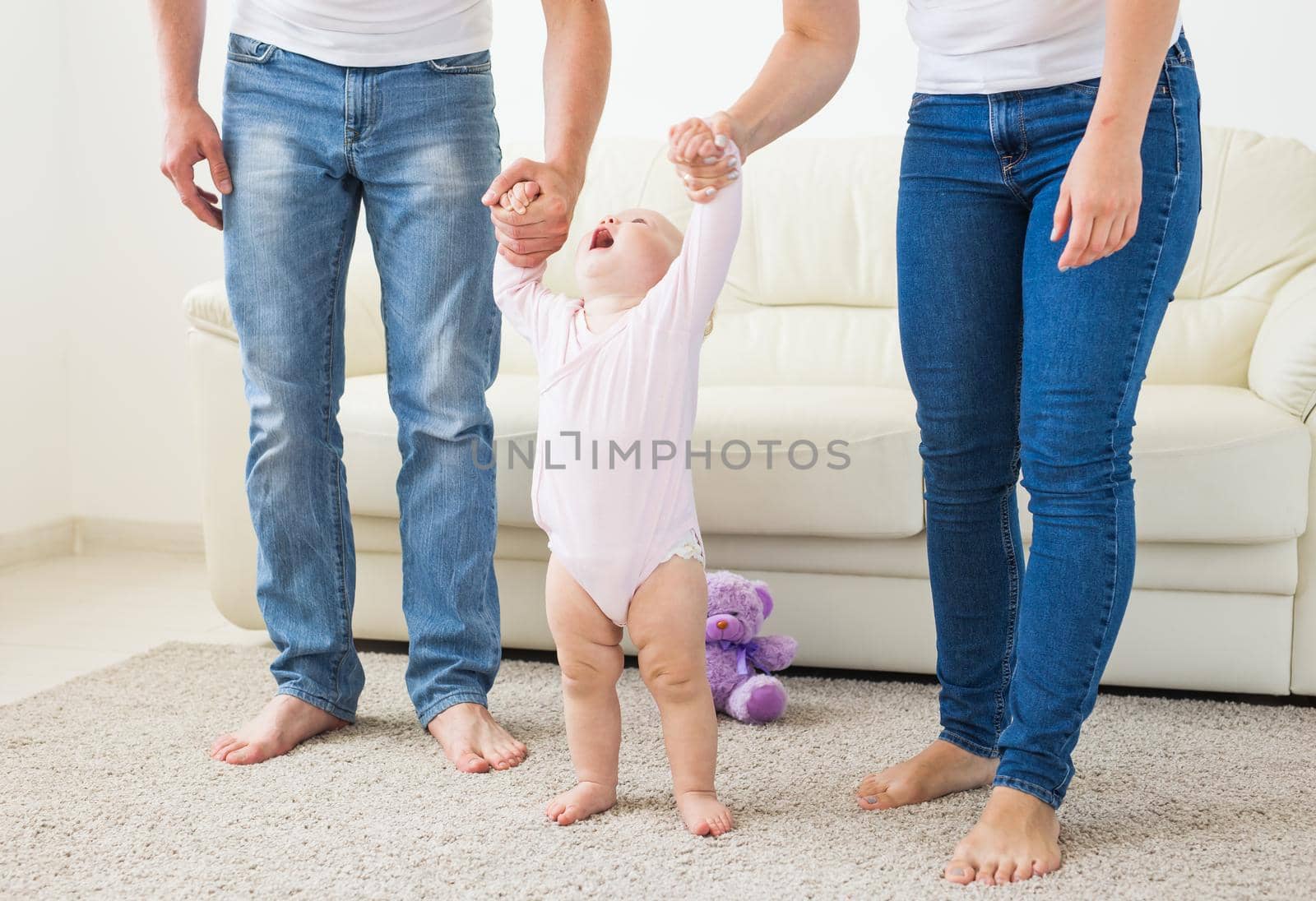 Family, children and parenthood concept - Parents teaching baby girl to walk by Satura86