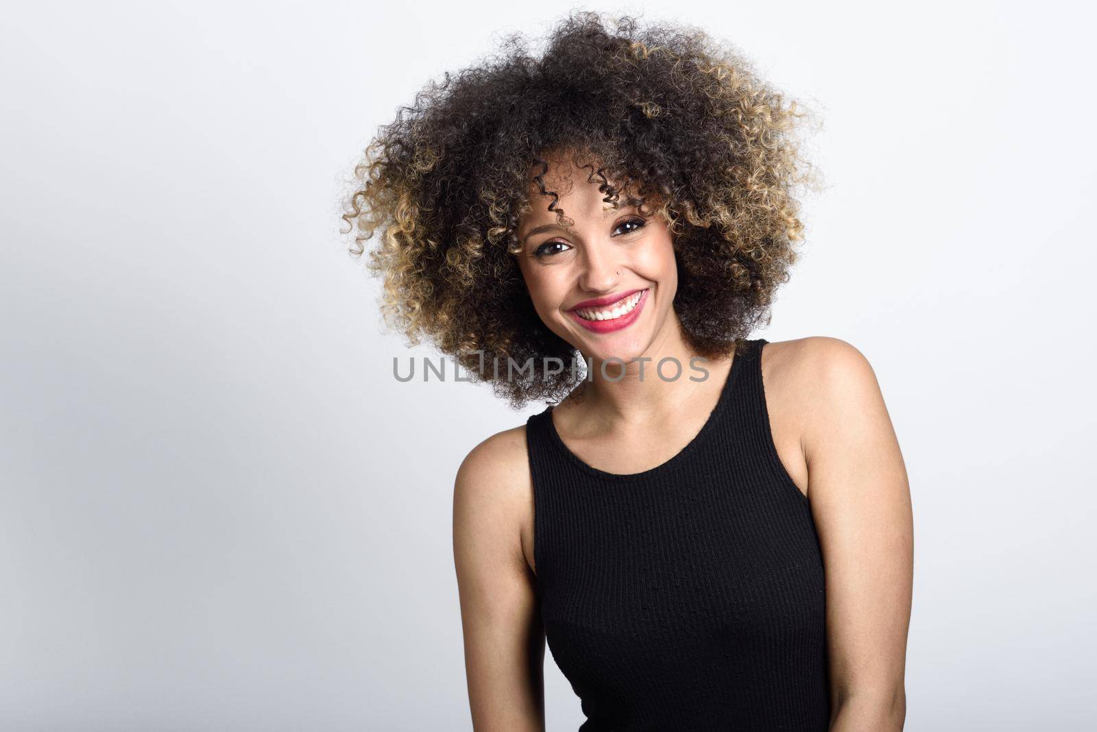 Young black woman with afro hairstyle smiling. Girl wearing black dress. Studio shot.
