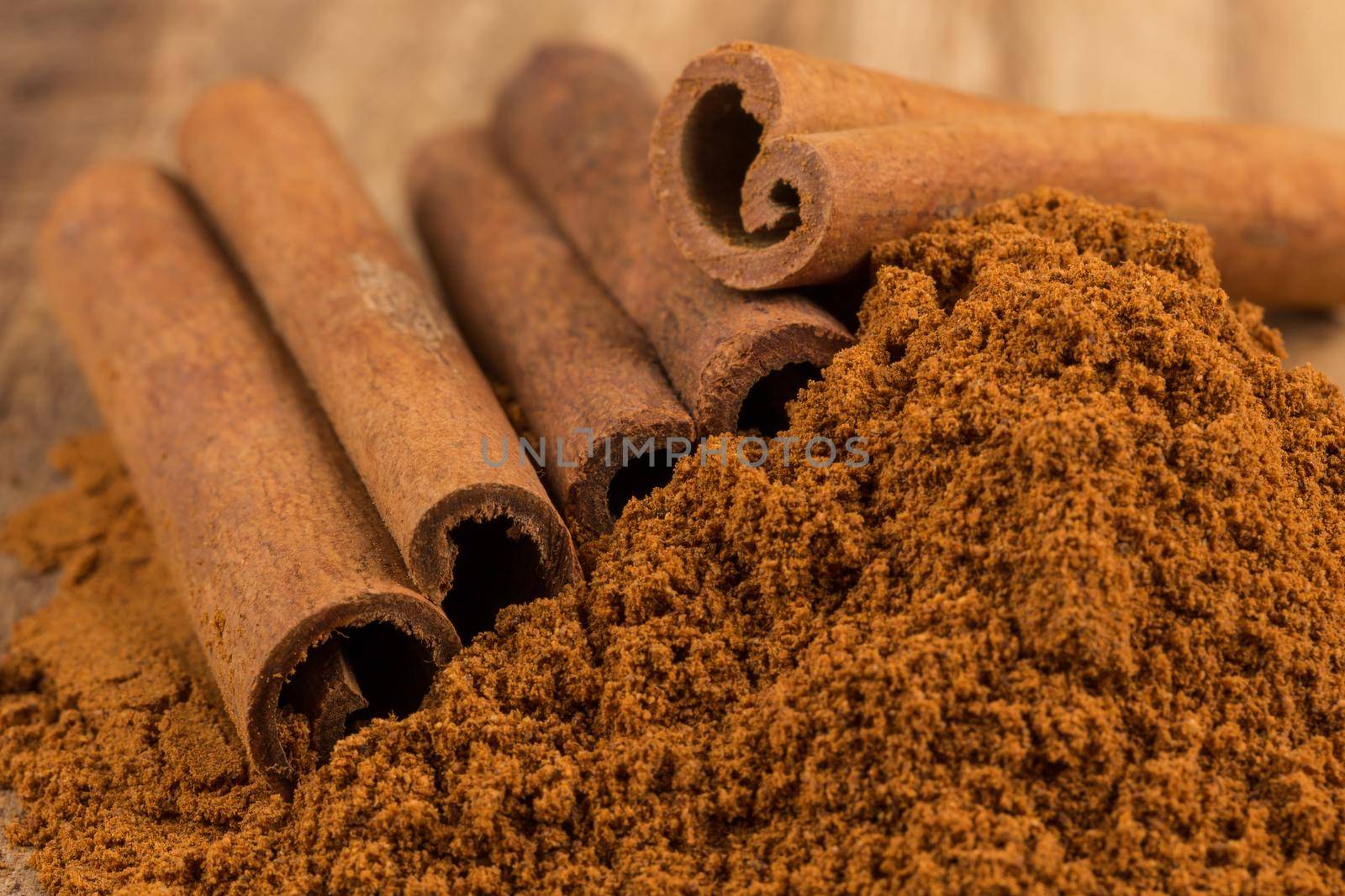 Cinnamon sticks with cinnamon powder on wooden background