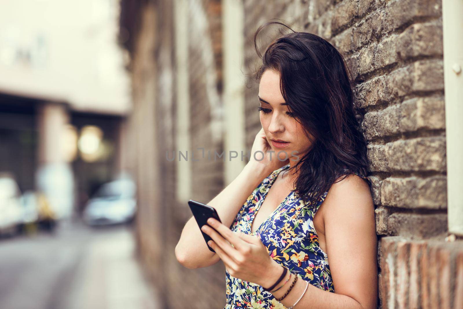 Serious young woman using her smart phone outdoors. by javiindy