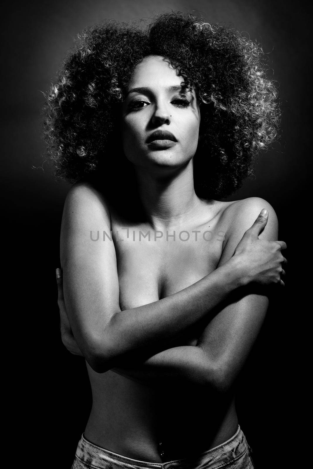 Young woman with afro hairstyle on black background. Studio shot.