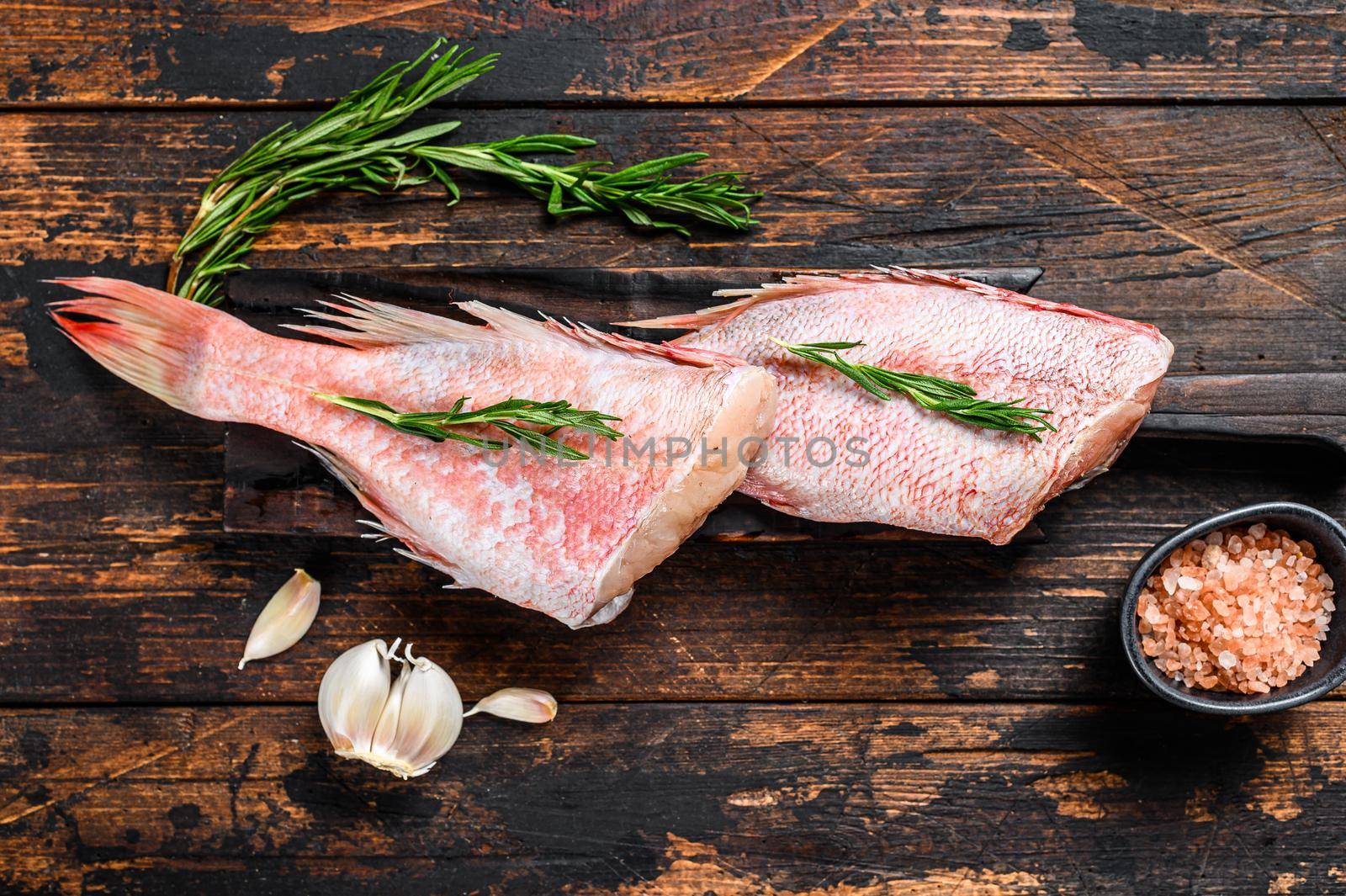 Whole raw fresh red perch or seabass fish. Dark wooden background. Top view.