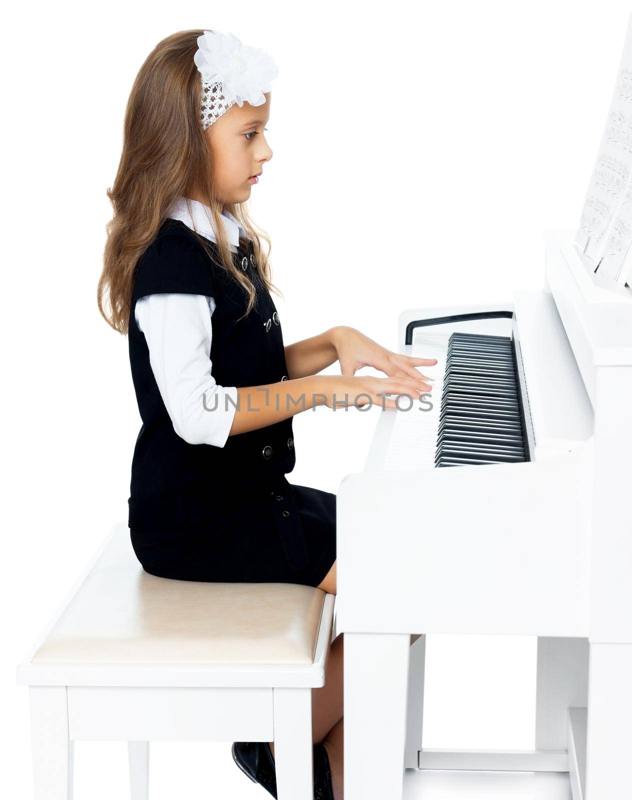 Beautiful little girl in the music school, learning to play the piano . the girl looks directly on the keys - Isolated on white background