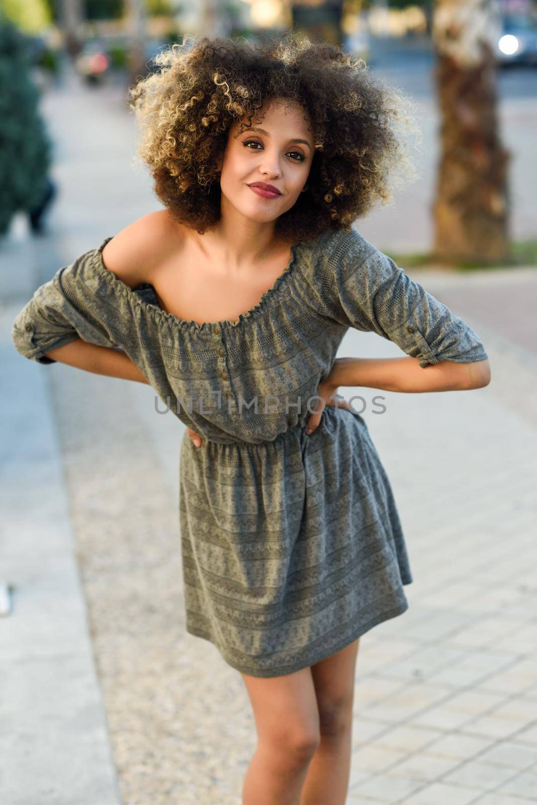 Young black woman with afro hairstyle smiling in urban background by javiindy