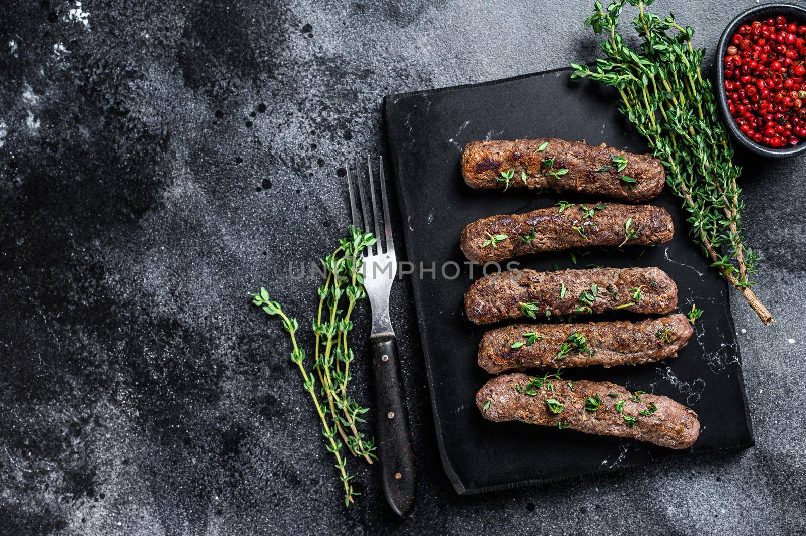 Grilled Shish kebab meat sausages. Black background. Top view. Copy space by Composter