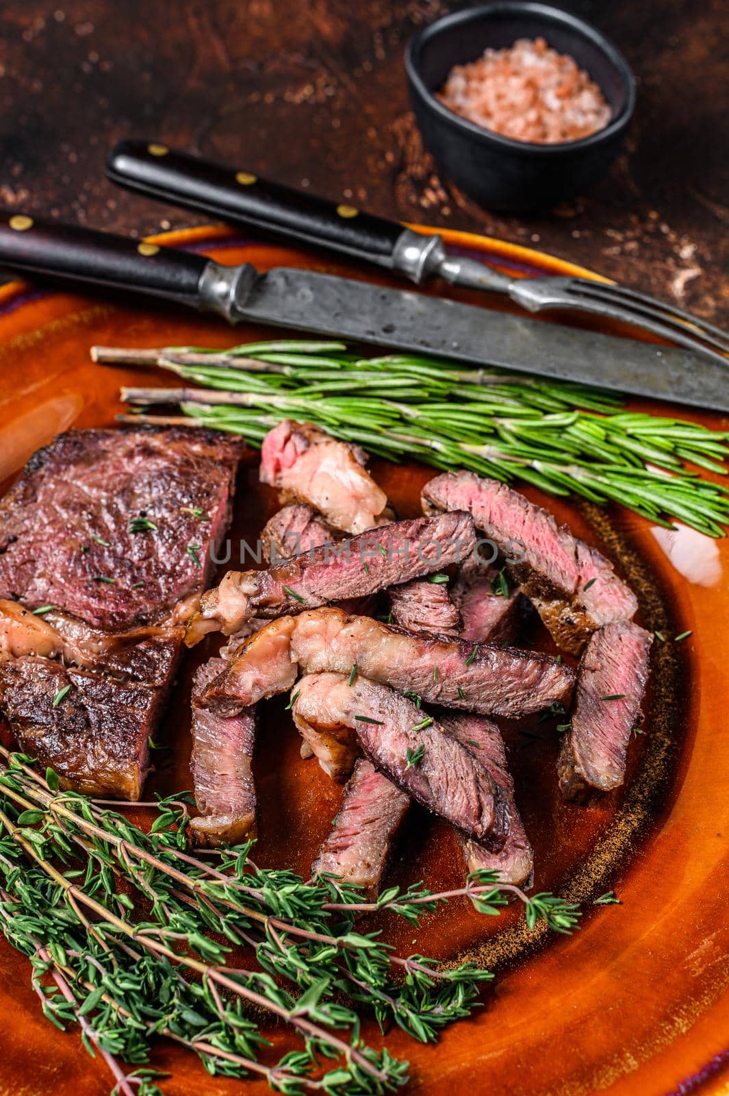 Grilled sliced rib eye or ribeye beef meat steak on a rustic plate. Dark background. Top view.