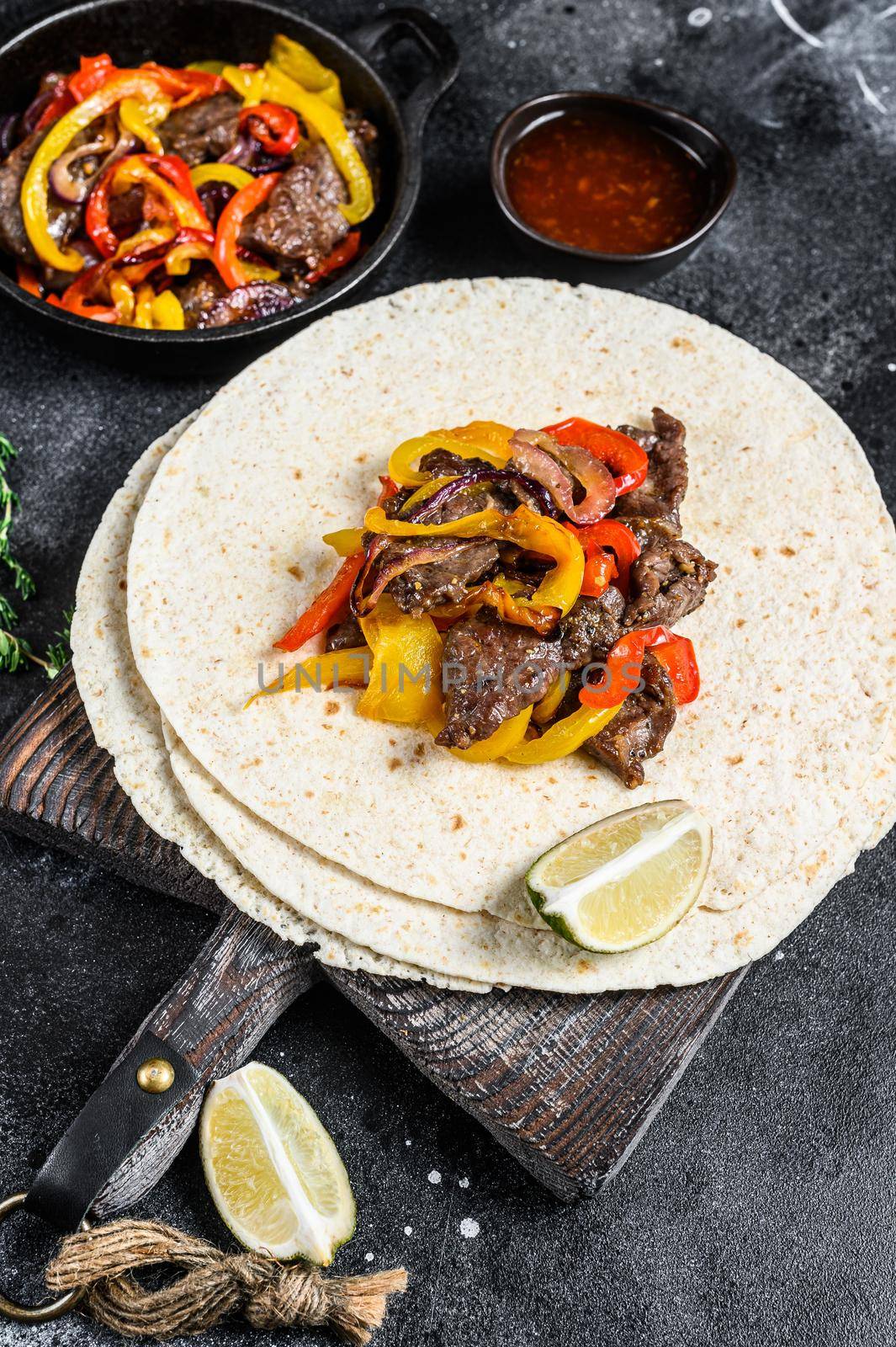 Beef Steak Fajitas with tortilla, mix pepper and onion traditional Mexican food. Black background. Top view by Composter