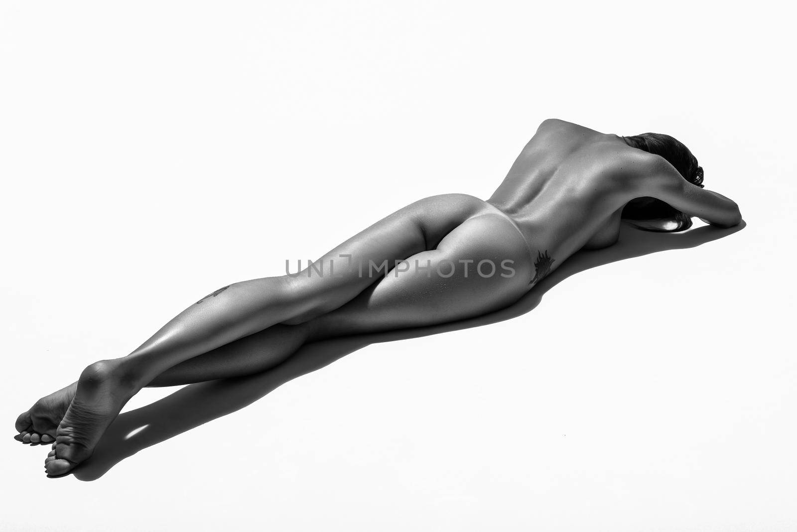 Young naked woman laying on white floor. Perfect skin. Black and white photograph