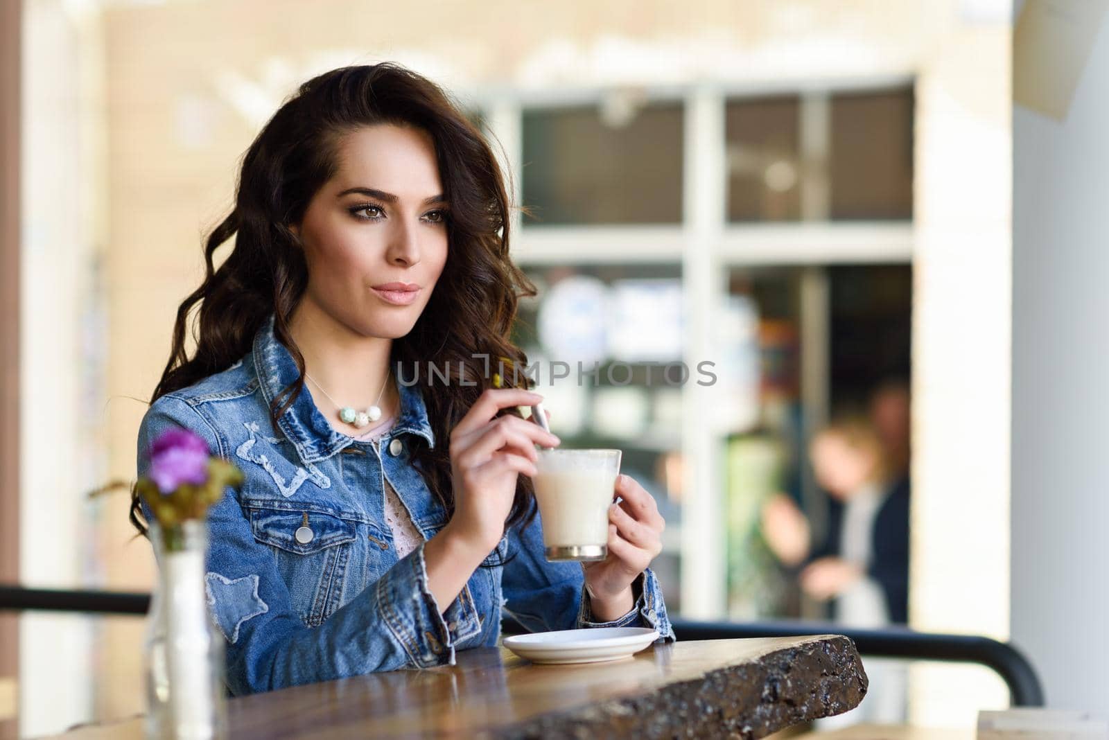 Young woman sitting indoor drinking coffee. Cool young modern caucasian female in her 20s. Cafe city lifestyle.