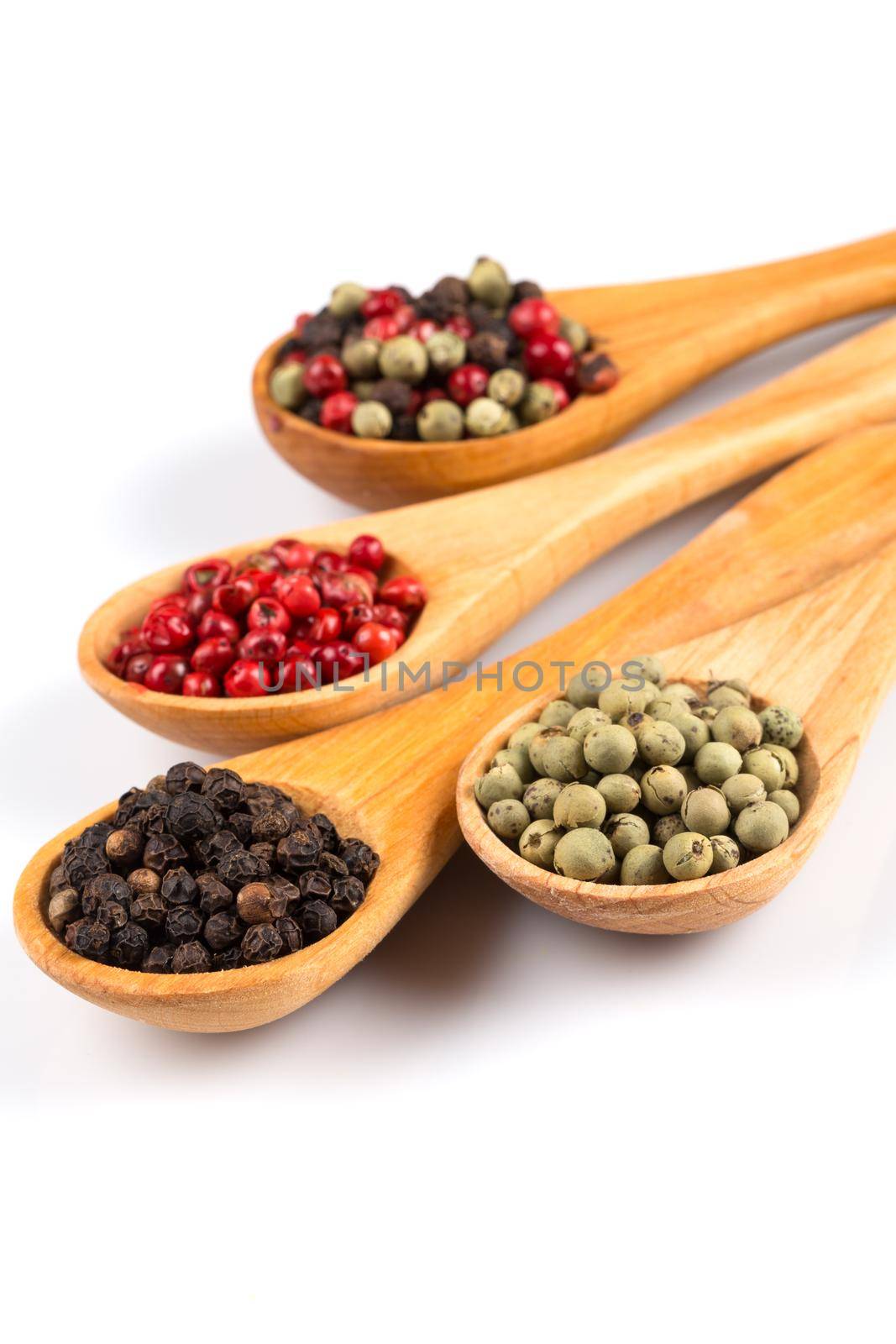 Wooden spoons with various pepper spice on white background