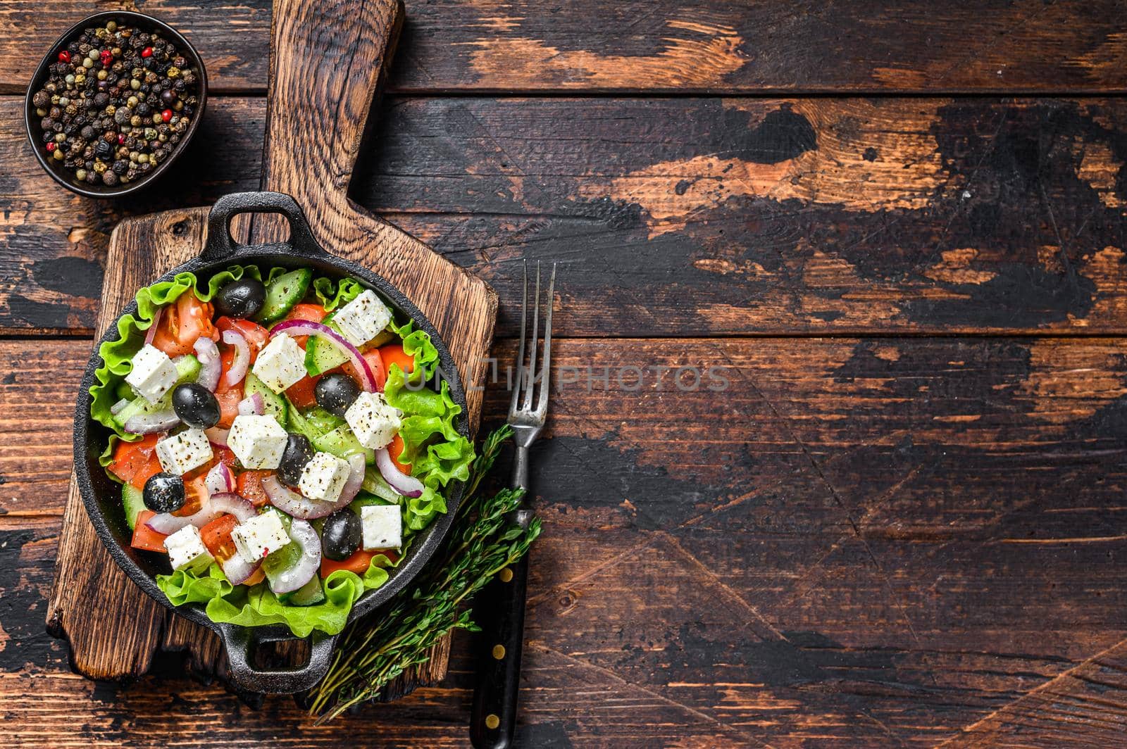 Greek salad with fresh vegetables and feta cheese in a pan. Dark Wooden background. Top view. Copy space.