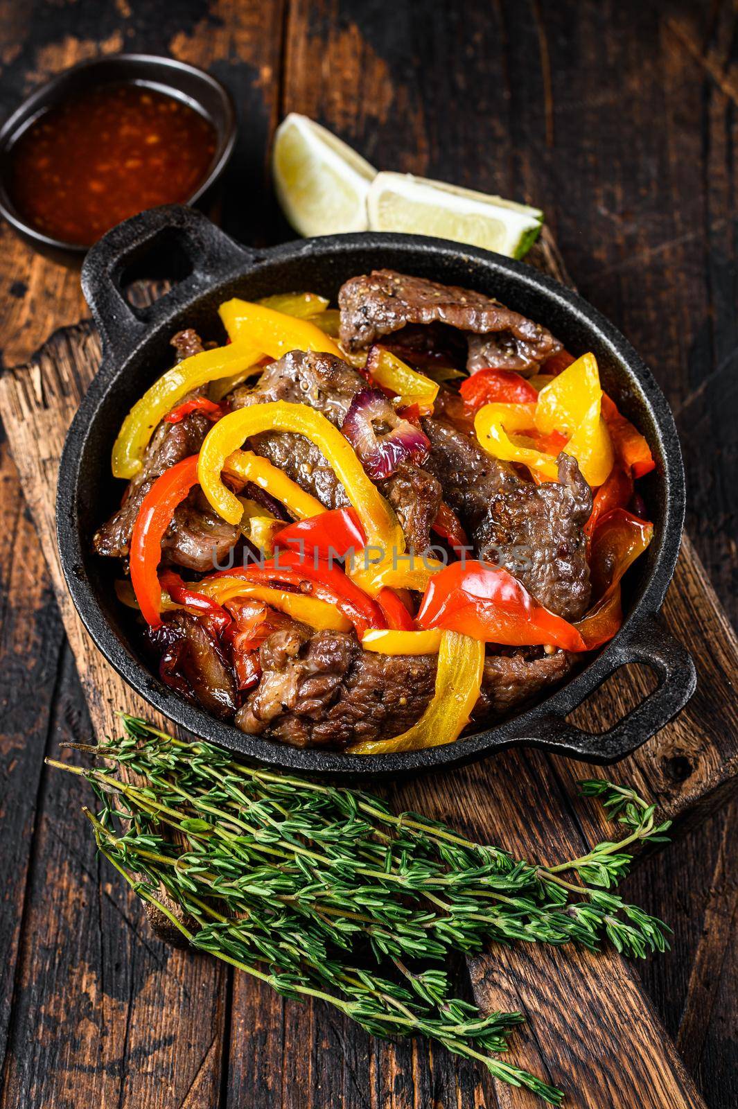 Fajitas beef meat traditional Mexican food dish in a pan. Dark wooden background. Top view.