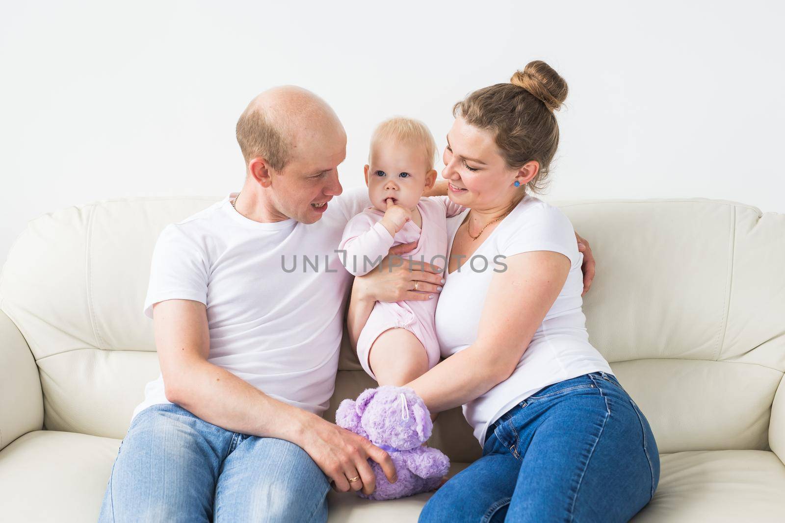 Proud mother and father smiling at their newborn baby daughter at home.