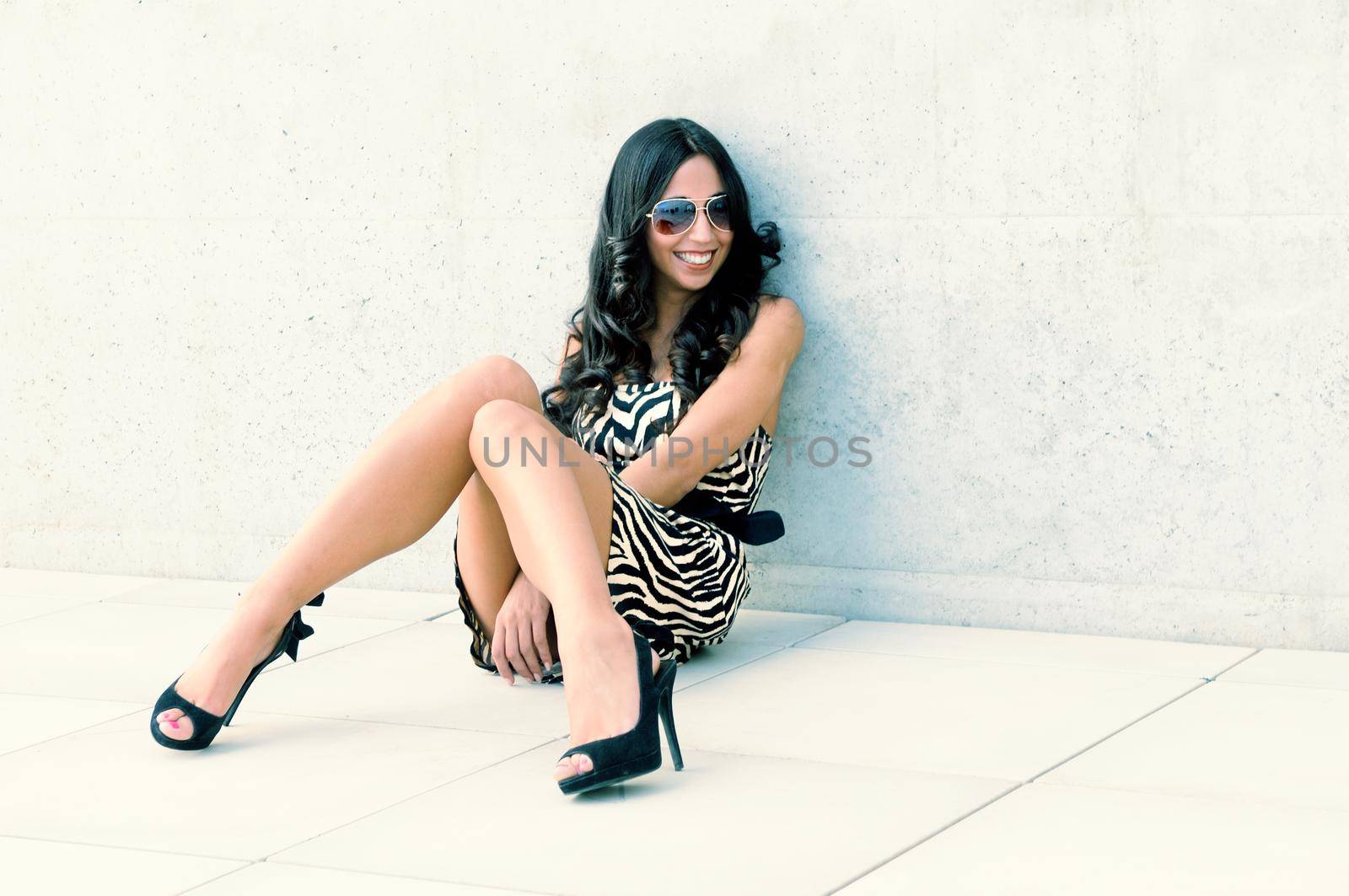 Funny female model at fashion with high heels sitting on the floor
