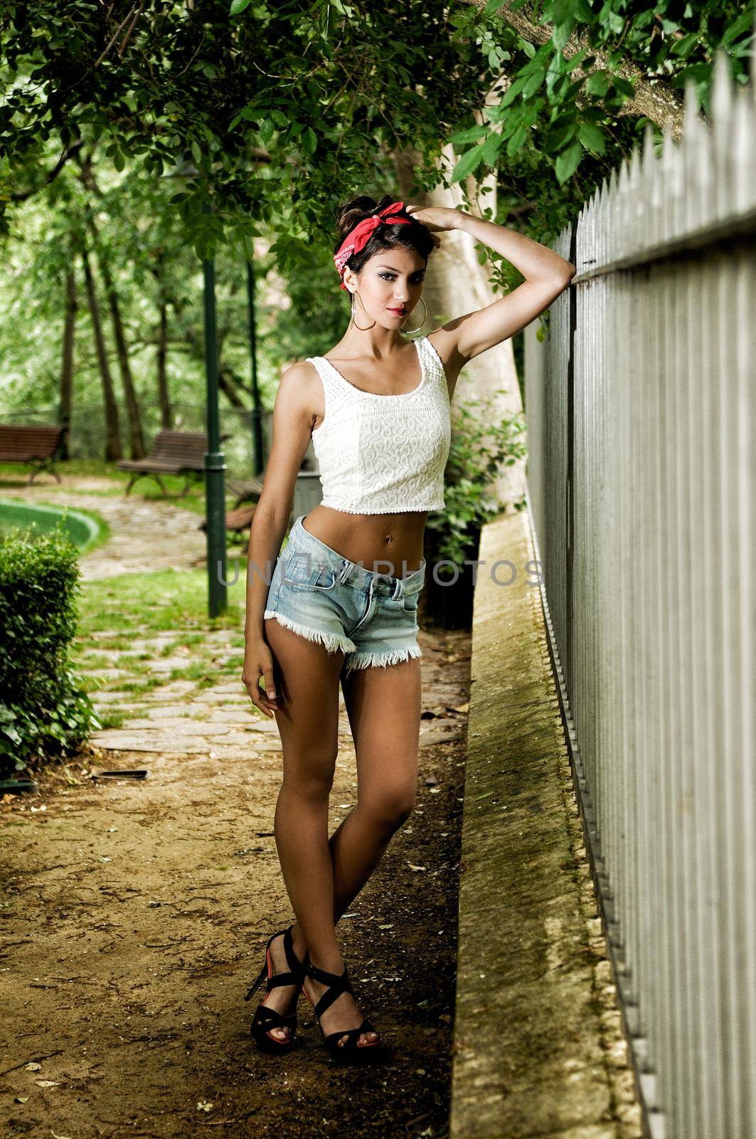 Portrait of a pin-up girl. American style, in a garden, wearing jeans and t-shirt