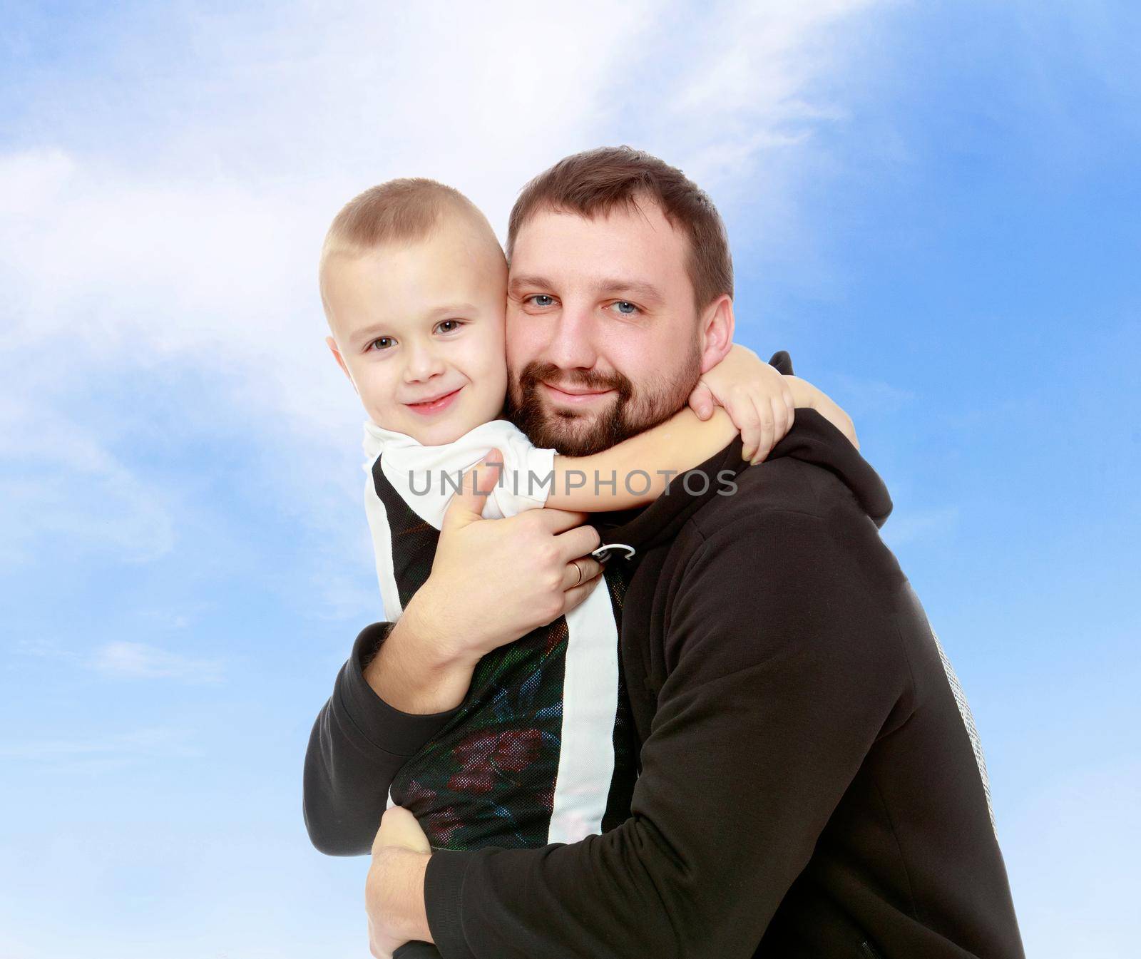 Happy family. Dad and son hug each other.On the background of summer blue sky and fluffy clouds.