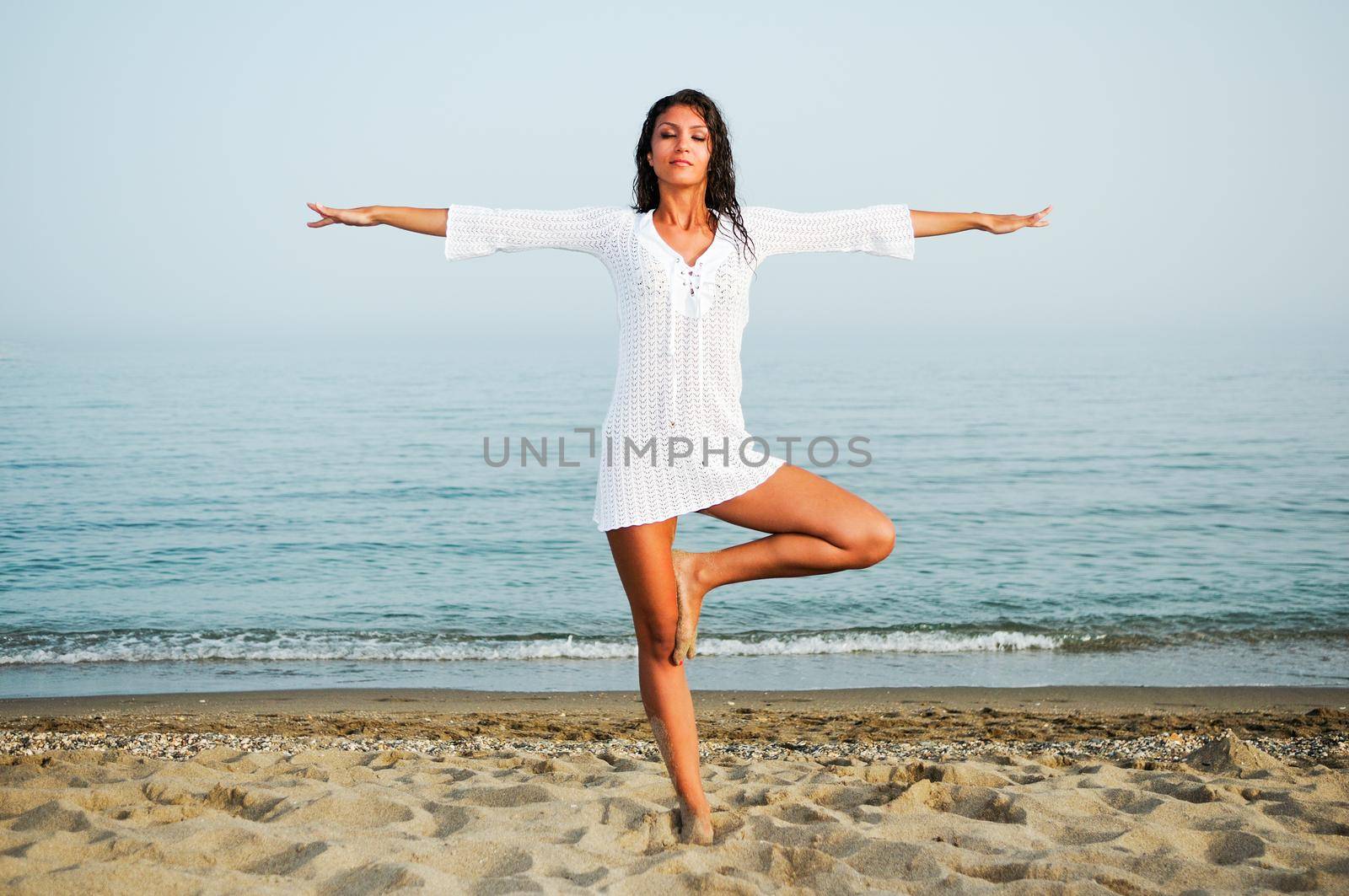 Pretty woman doing yoga on the beach