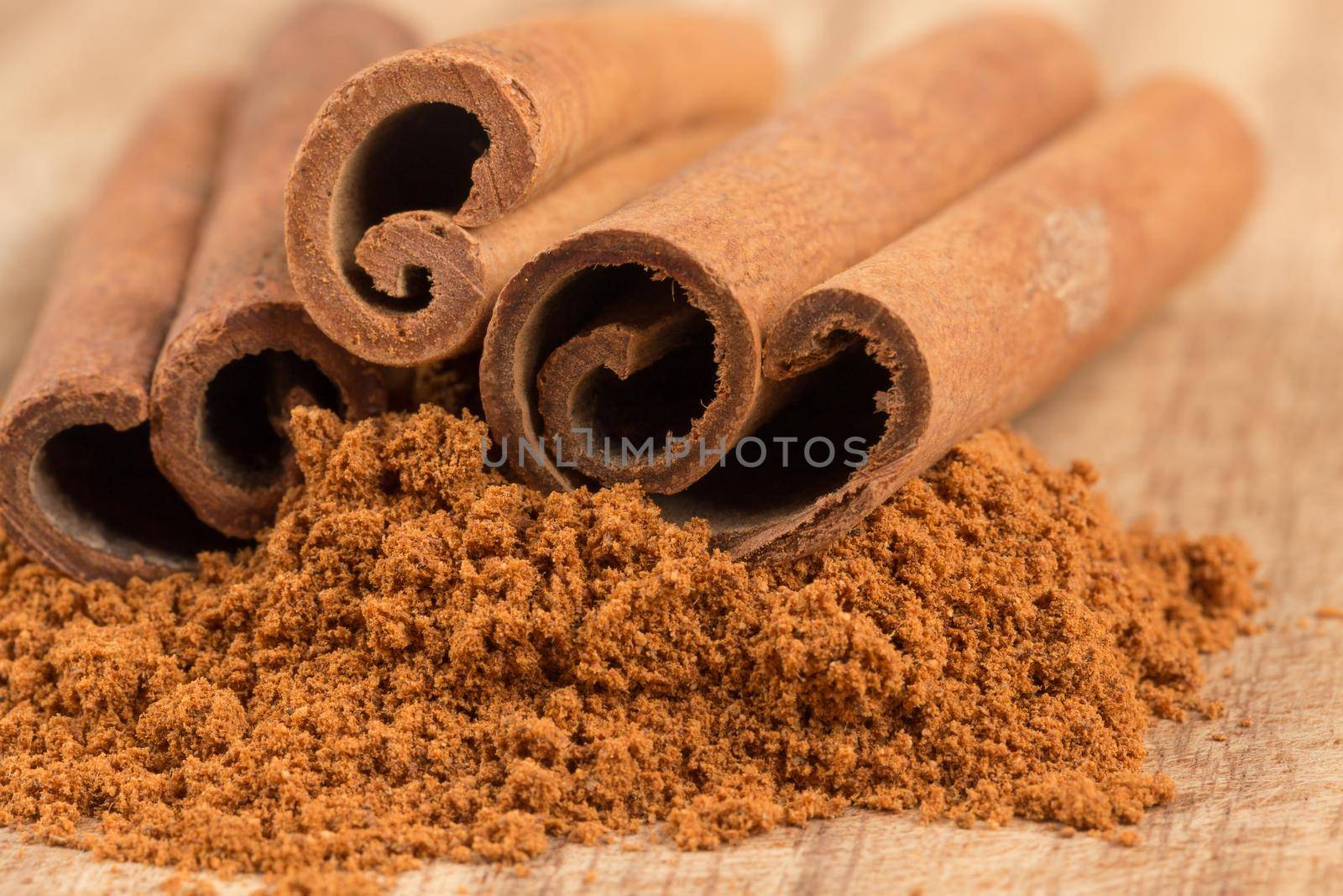 Cinnamon sticks with cinnamon powder on wooden background