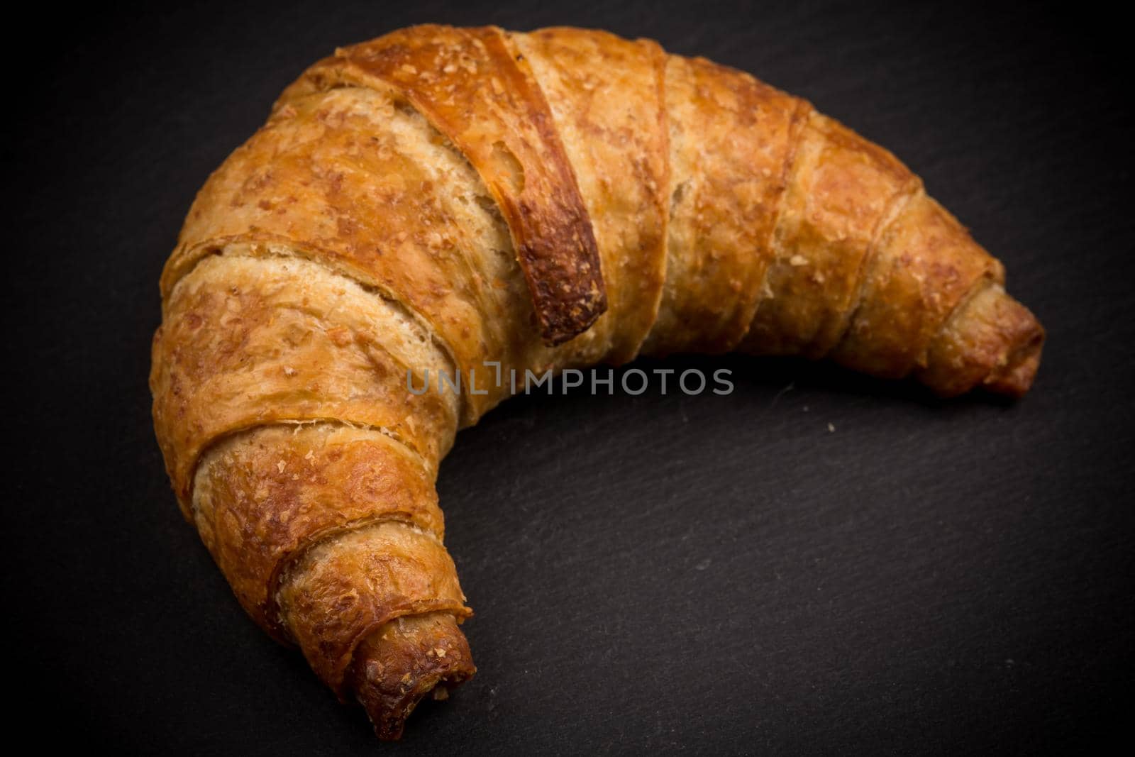 Fresh and tasty croissant on dark stone plate