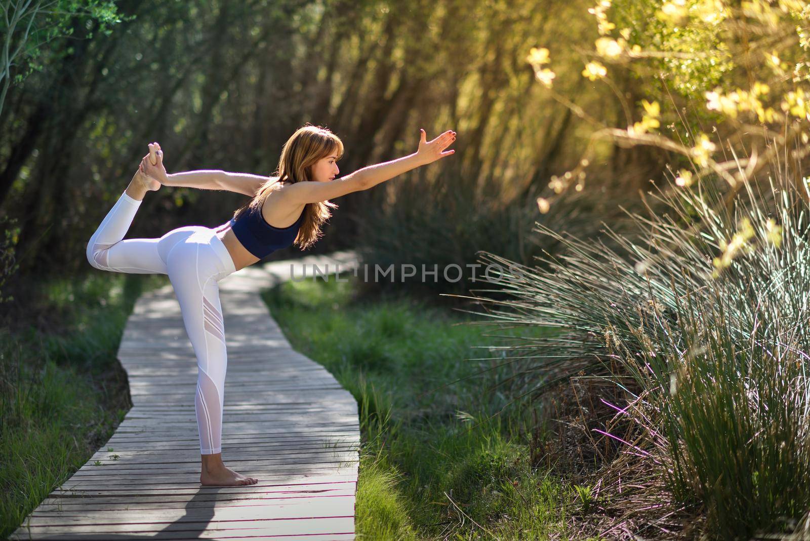 Young woman doing yoga in nature. Female wearing sport clothes.