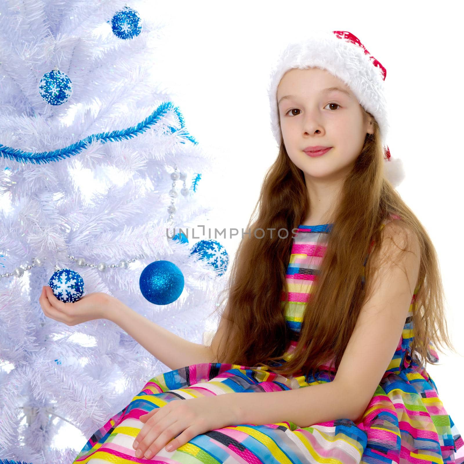 A happy little girl is decorating a Christmas tree. The concept of holidays, Christmas and New Year. Isolated on white background.