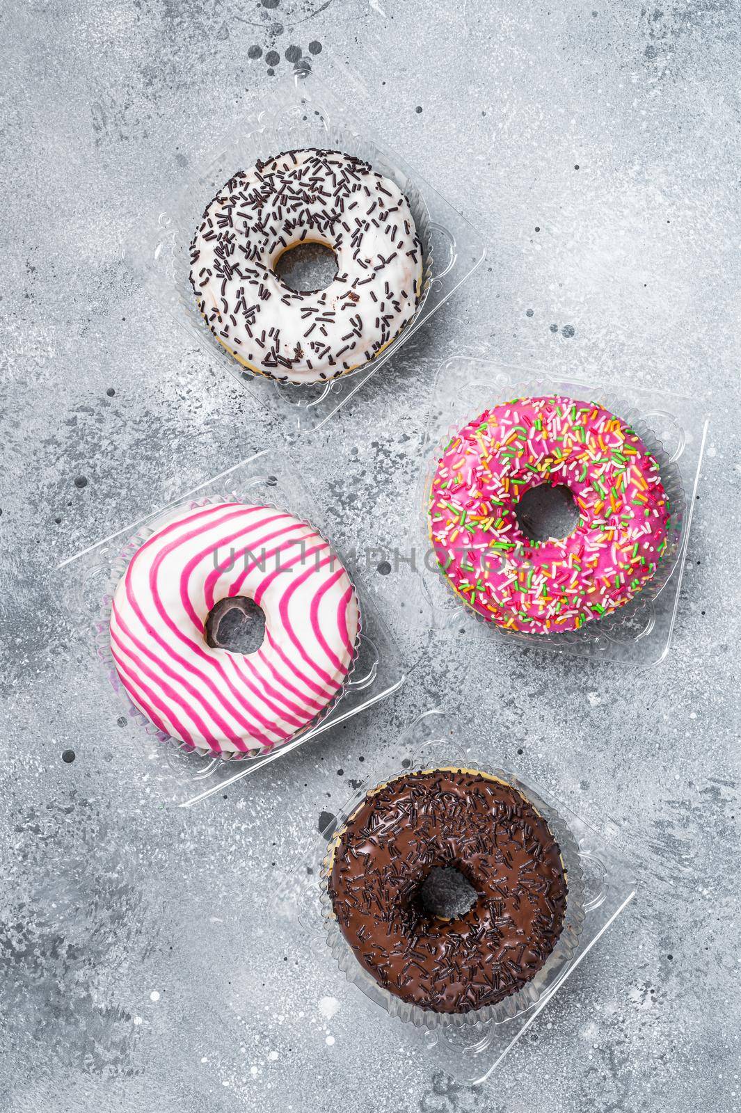 Assorted glazed donuts on a kitchen table. Gray background. Top view.