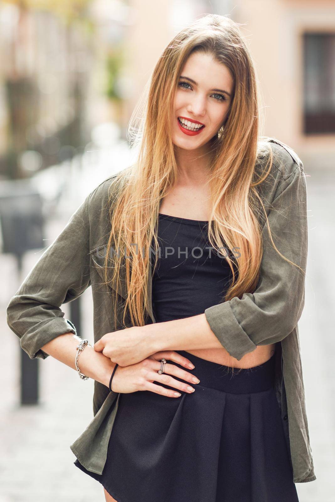 Portrait of happy blonde girl smiling in urban background