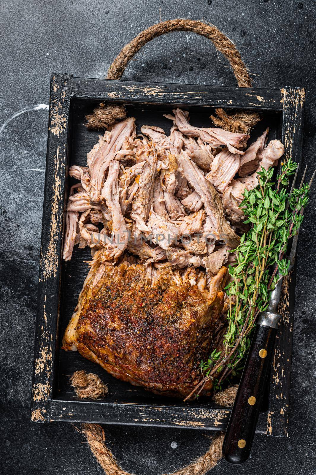 Bbq slow roast puilled pork meat in a wooden tray. Black background. Top view by Composter