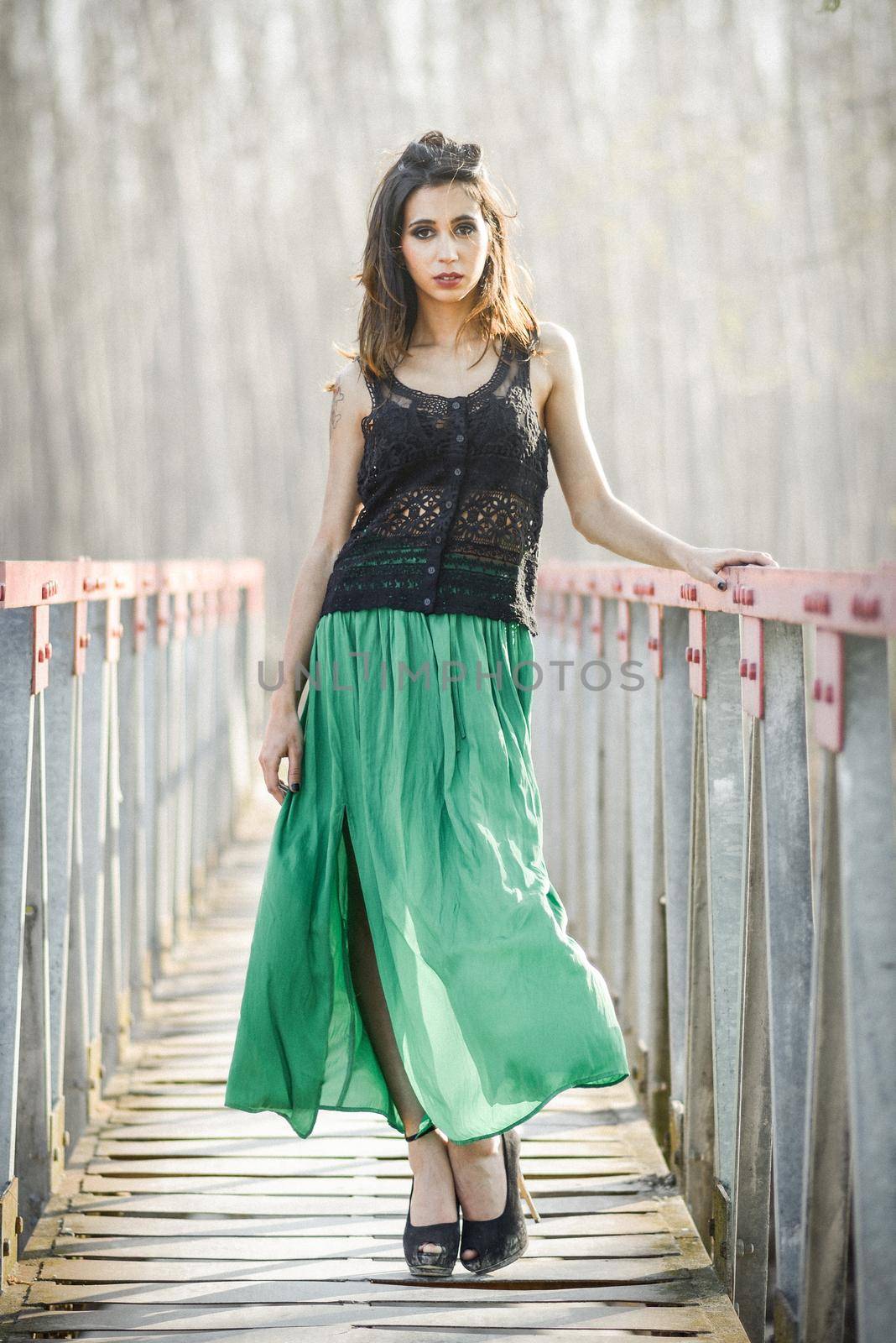 Portrait of beautiful young woman wearing long dress in a rural bridge