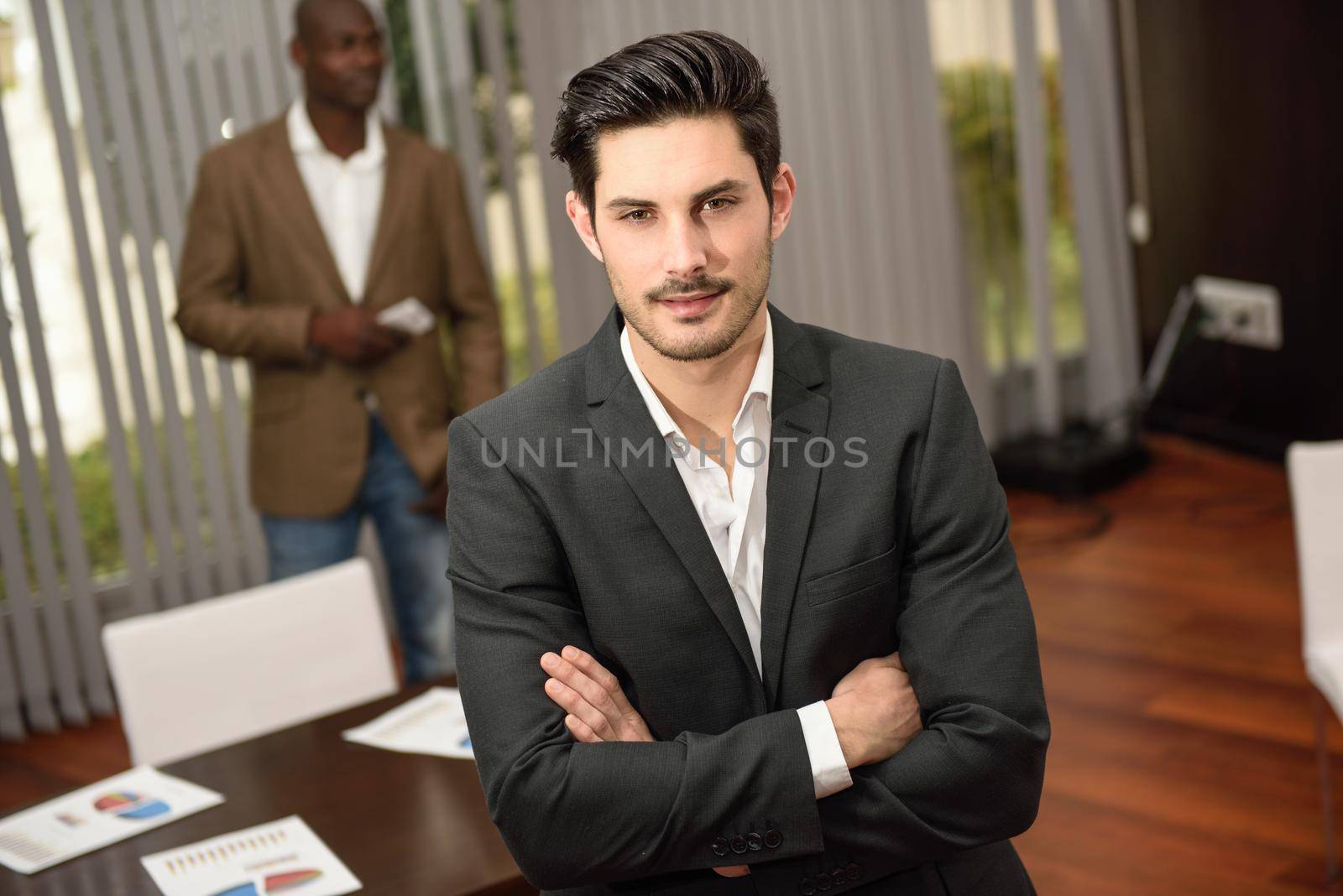 Cheerful young businessman in formalwear keeping arms crossed by javiindy