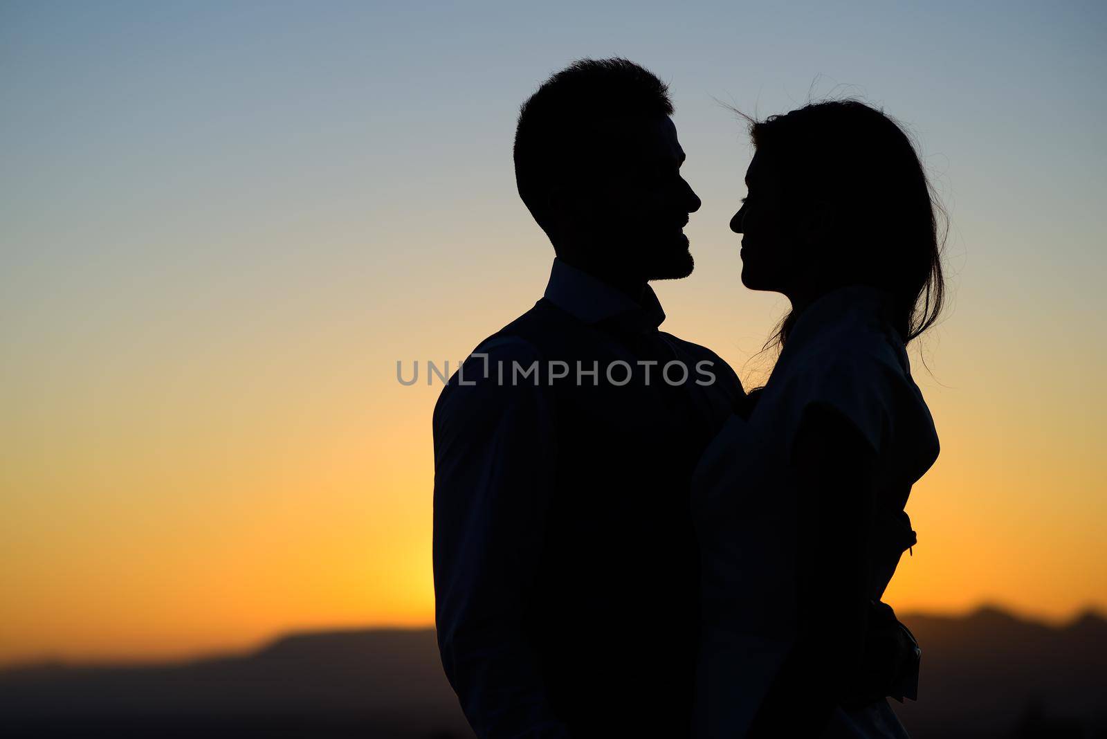 Silhouette of a young bride and groom on Sunset background