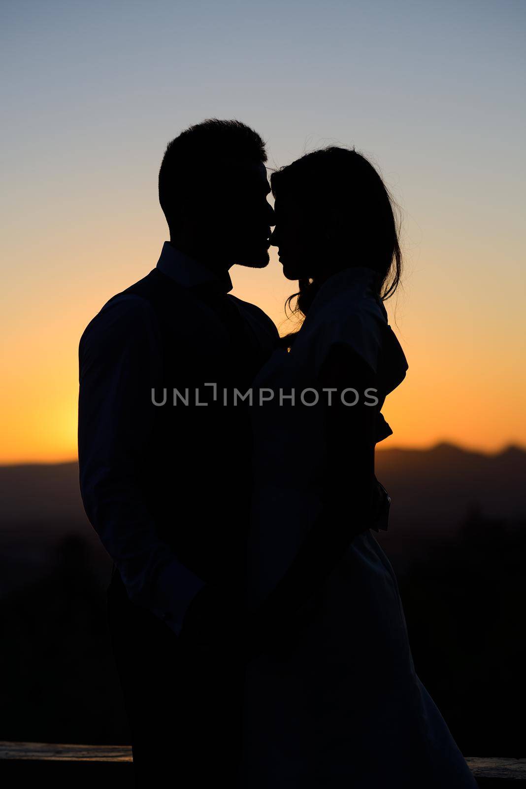 Silhouette of a young bride and groom on Sunset background