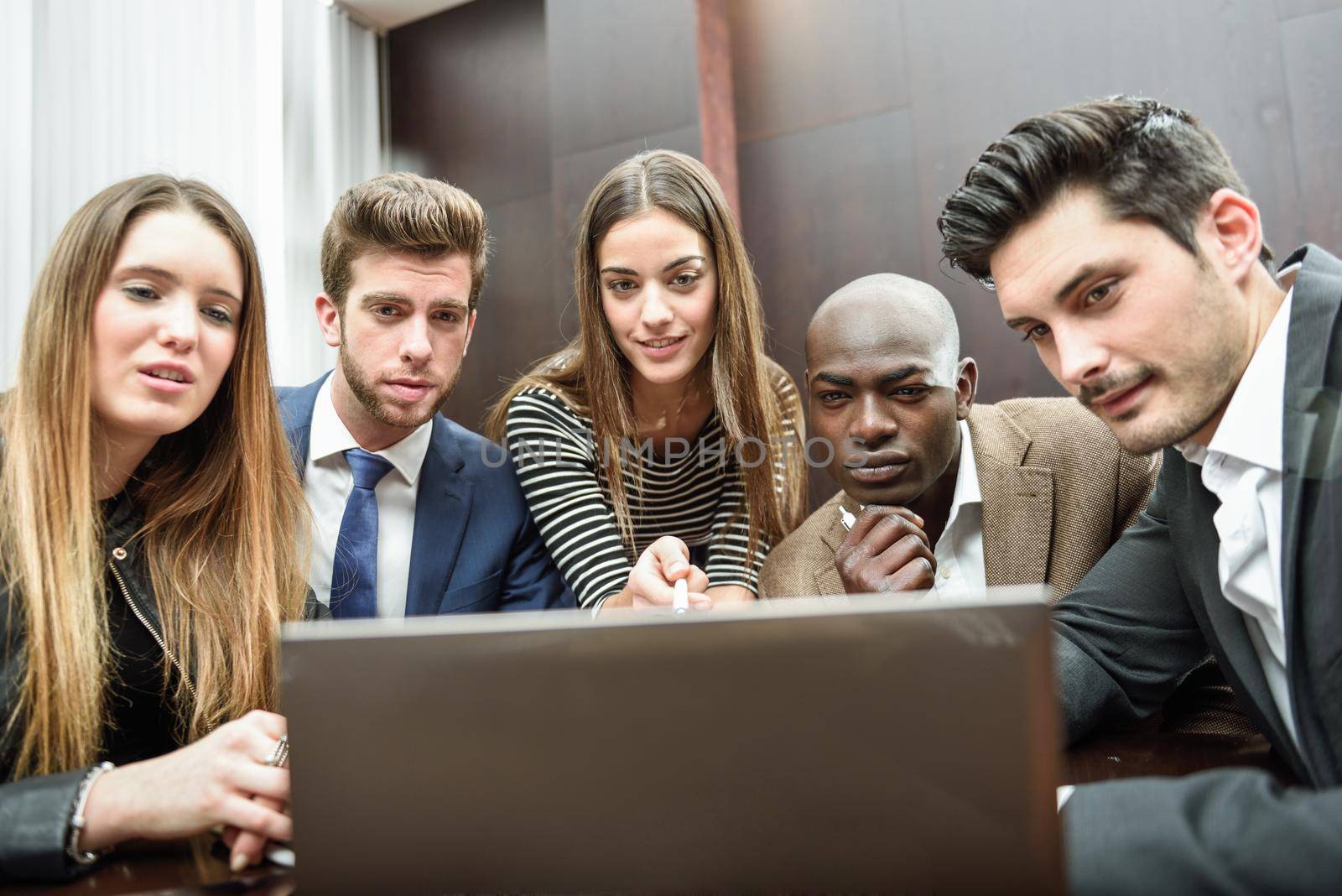 Businesspeople, teamwork. Group of multiethnic busy people looking at a laptop