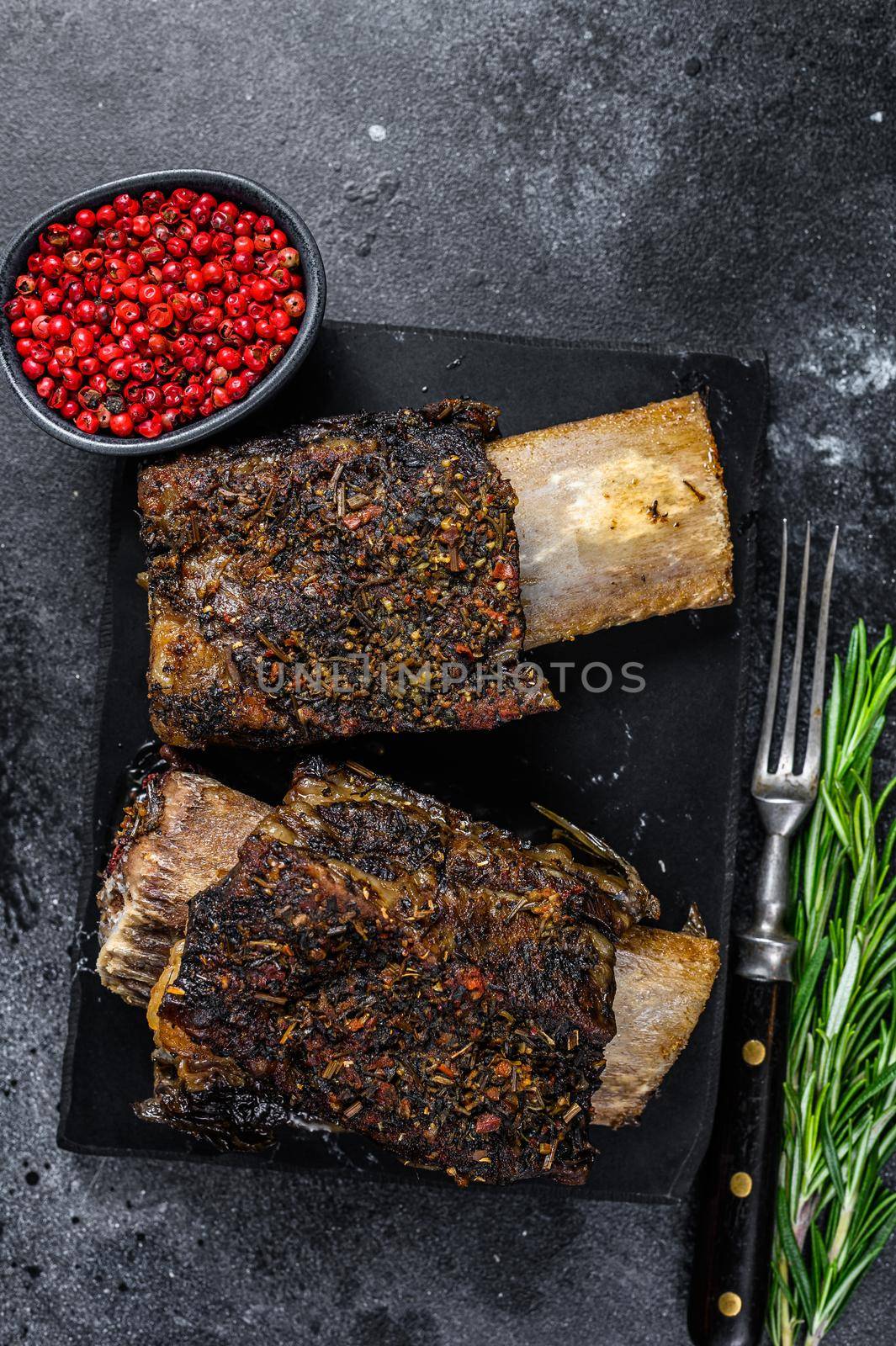 BBQ Beef Short Ribs with herbs. Black background. Top view.