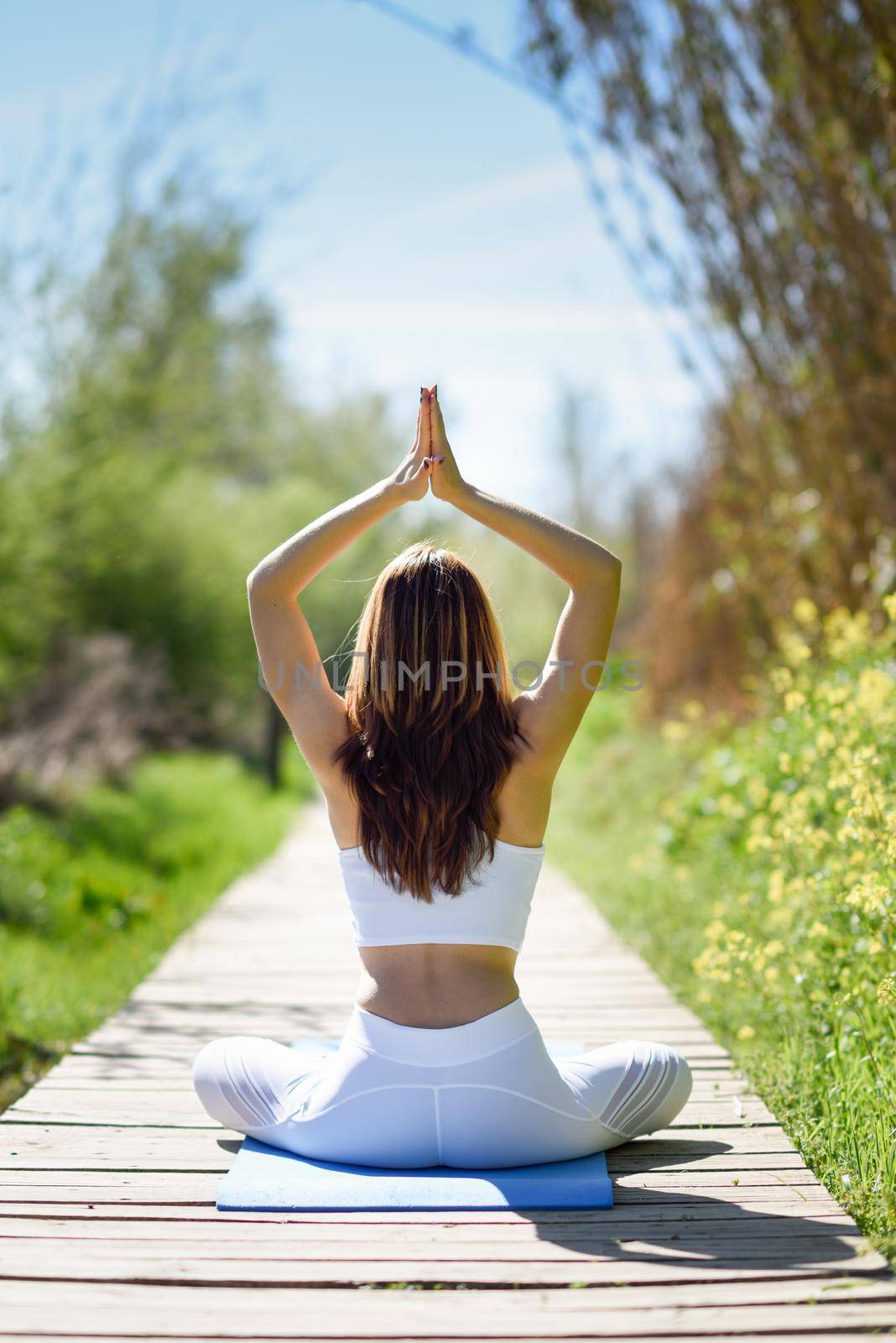 Young woman doing yoga in nature. Female wearing white sport clothes in lotus figure.