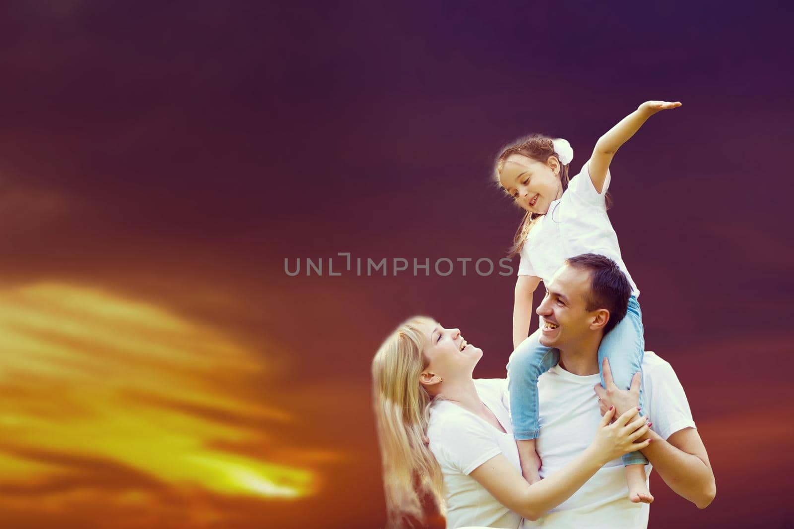 young happy family having fun outdoors, dressed in white and on sky and sunset