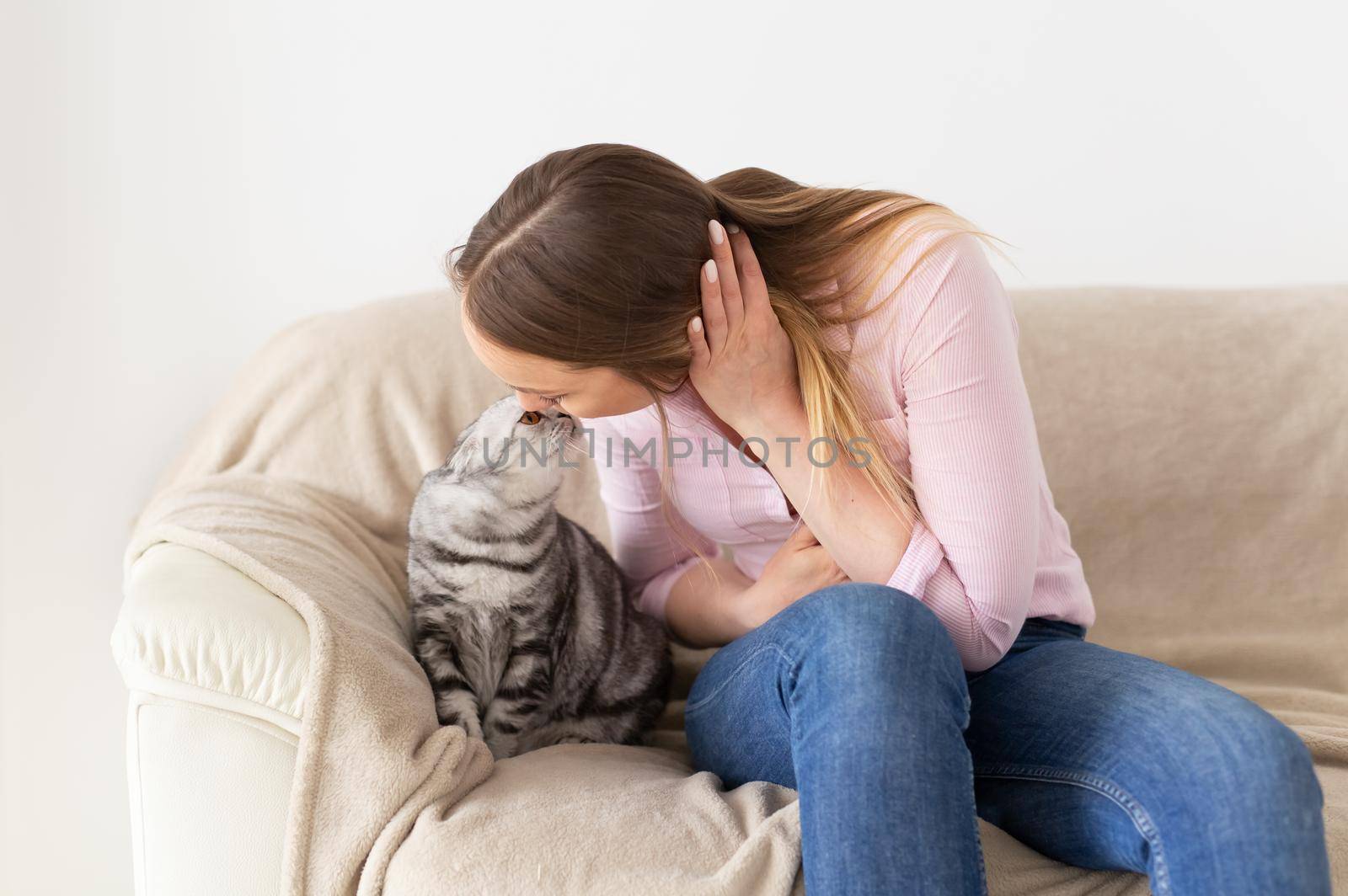 Woman at home kissing her lovely fluffy cat. Gray tabby cute scottish fold cat. Pets and lifestyle concept