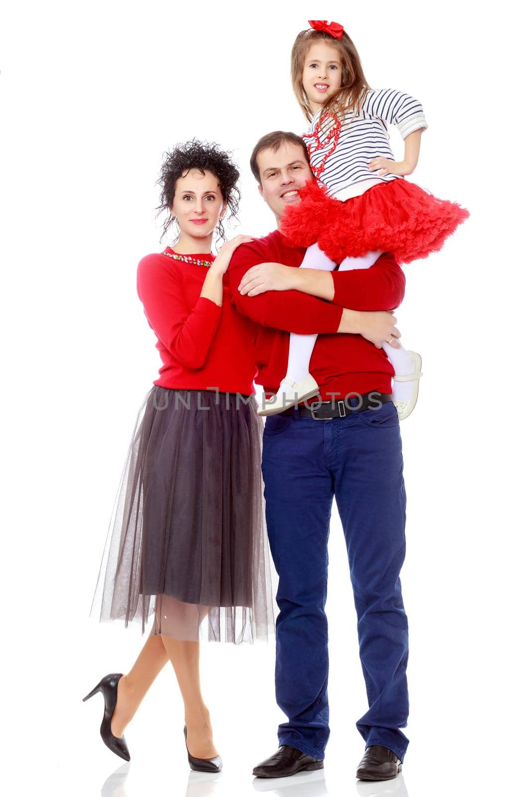 Happy young family dad mom and a little girl in bright red outfits . Dad holds daughter on hands.Isolated on white background.