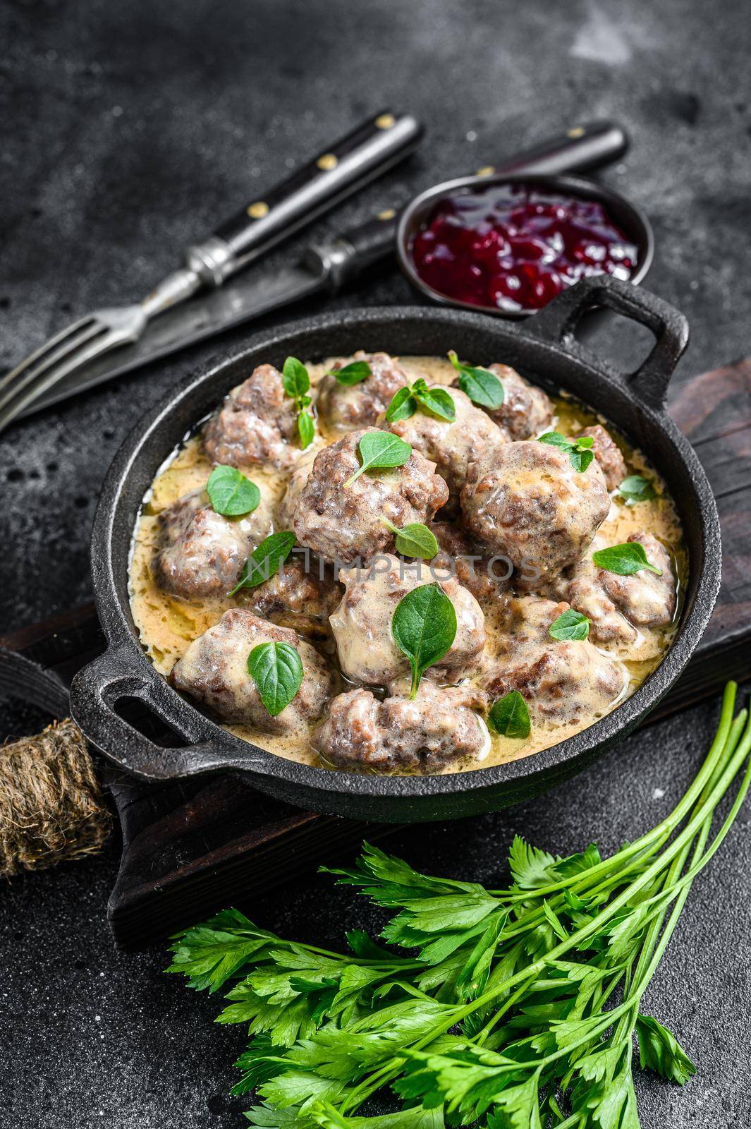Beef meatballs in cream sauce in a frying pan. Black background. Top view by Composter