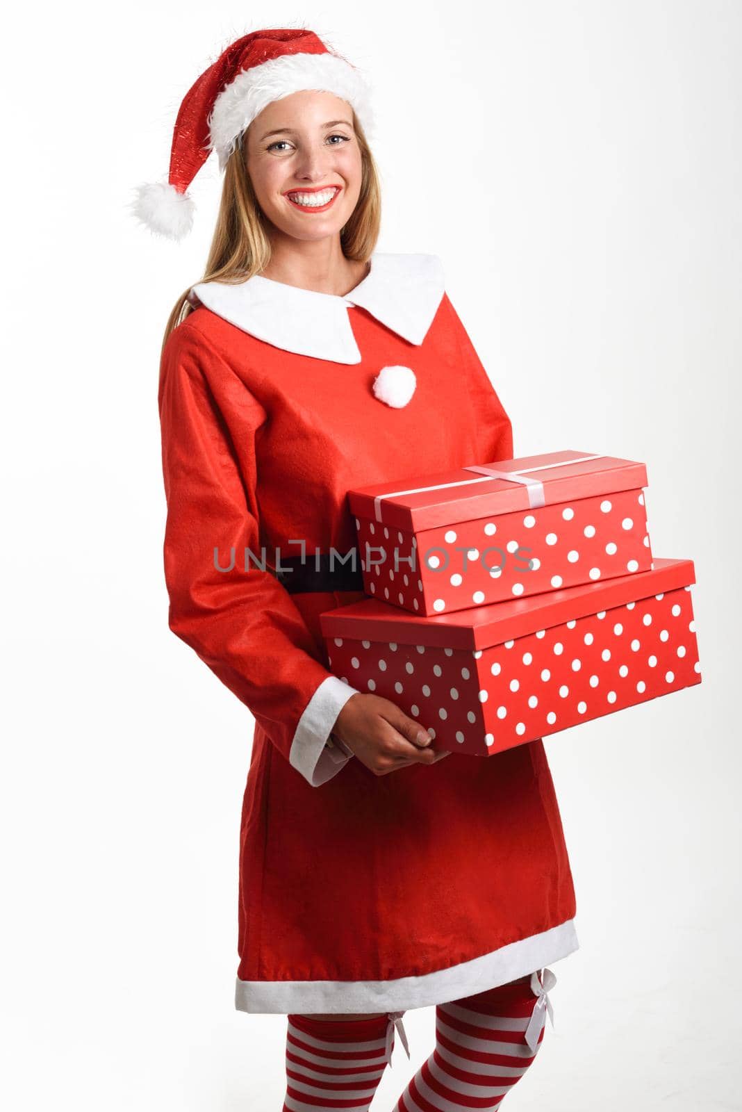 Blonde woman in Santa Claus clothes smiling with gift boxes in her hands. Young female with blue eyes, isolated on white
