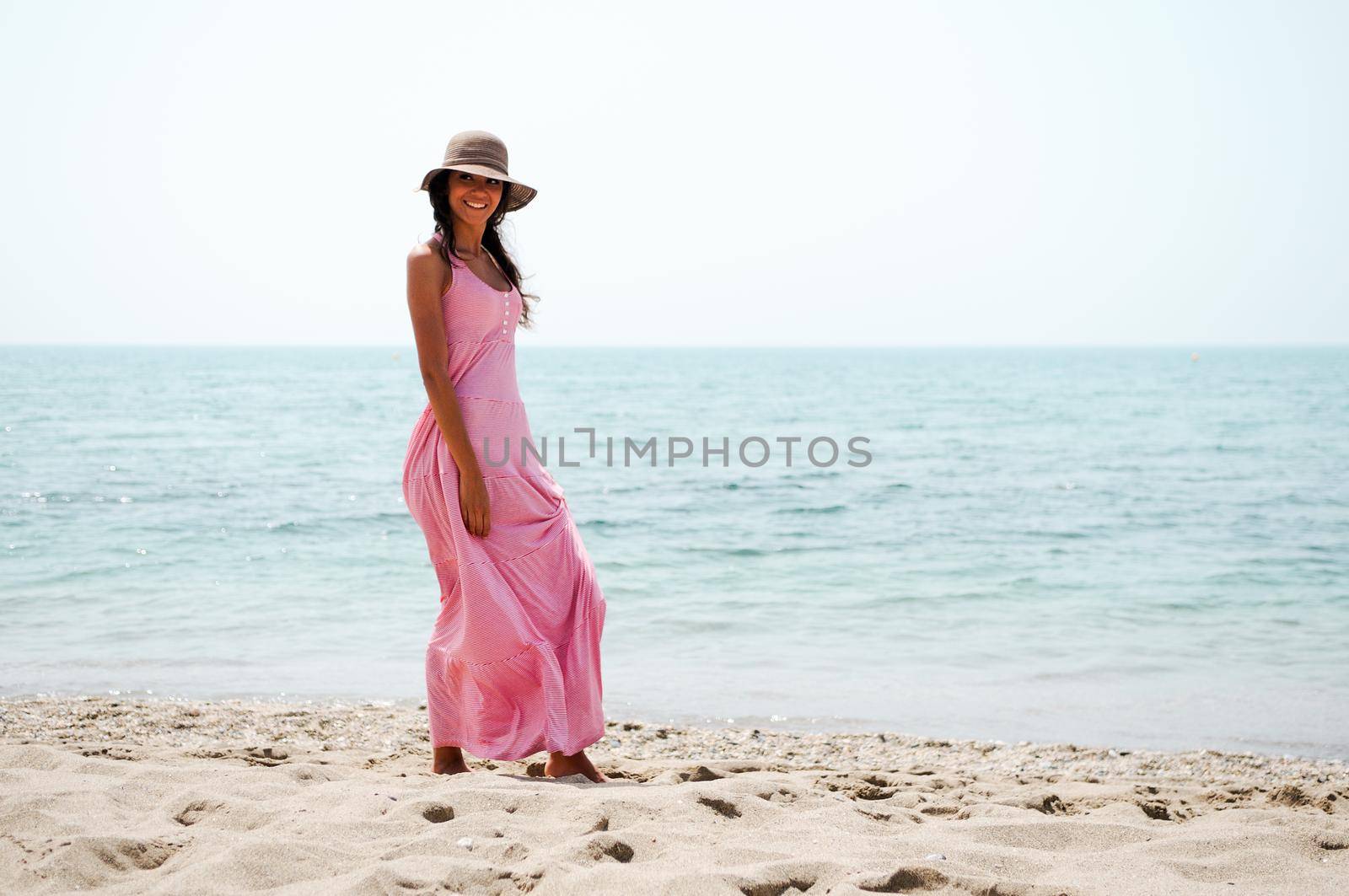 Portrait of a beautiful woman with long pink dress on a tropical beach