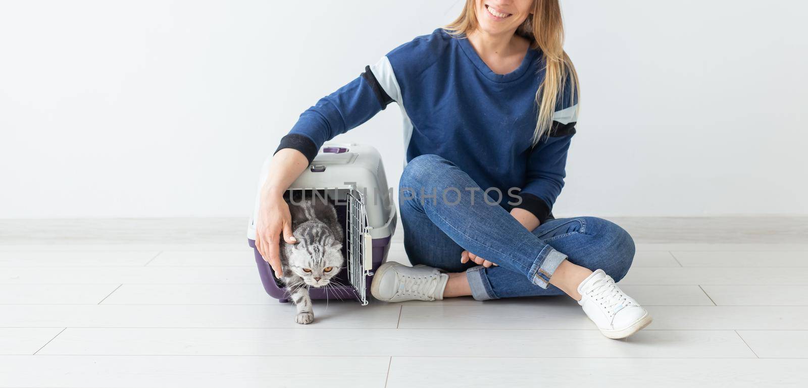 Positive good-looking woman and beautiful gray Scottish Fold cat into her new apartment after the move. Housewarming and pets concept