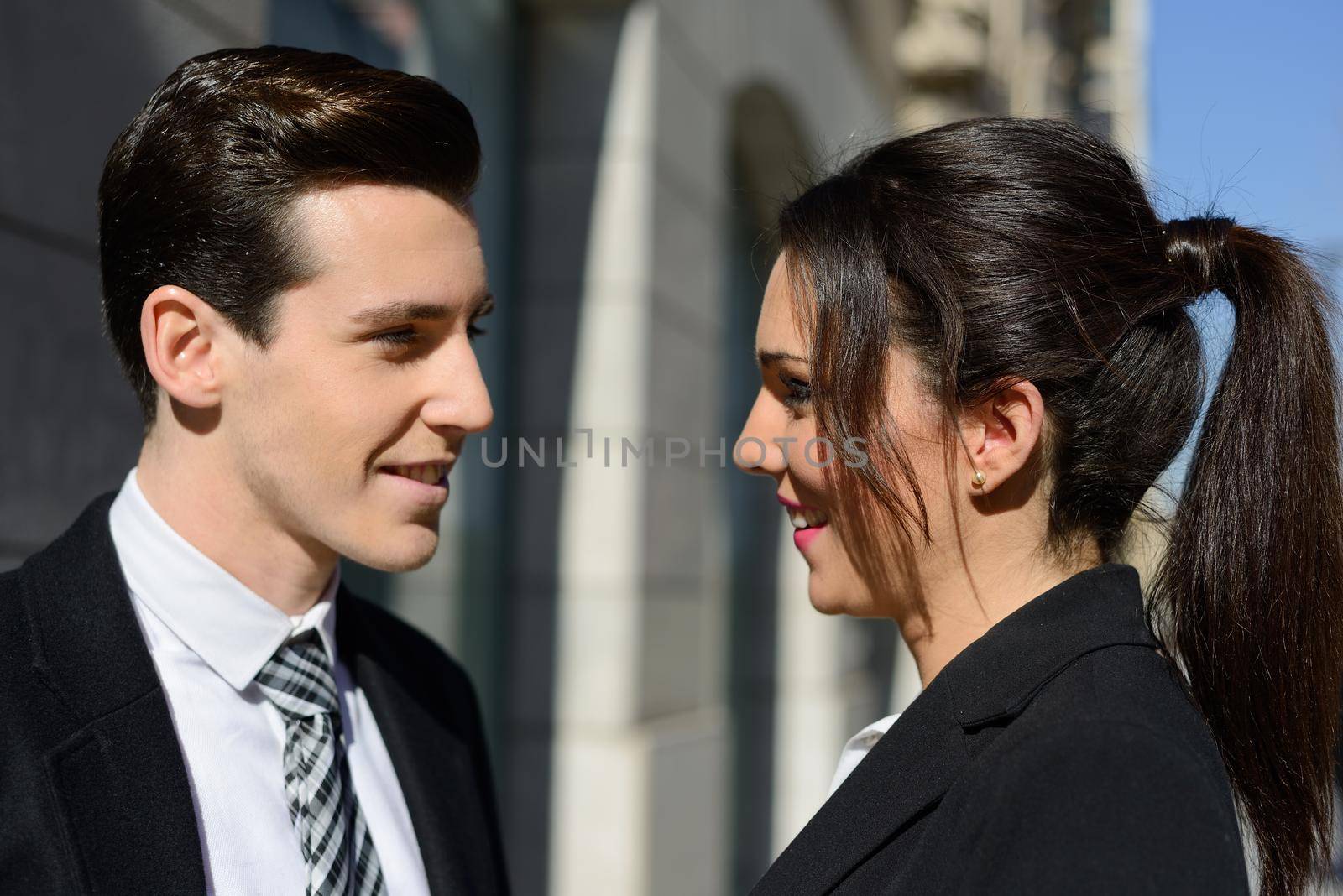 Attractive business people talking outside of company building. Couple working.