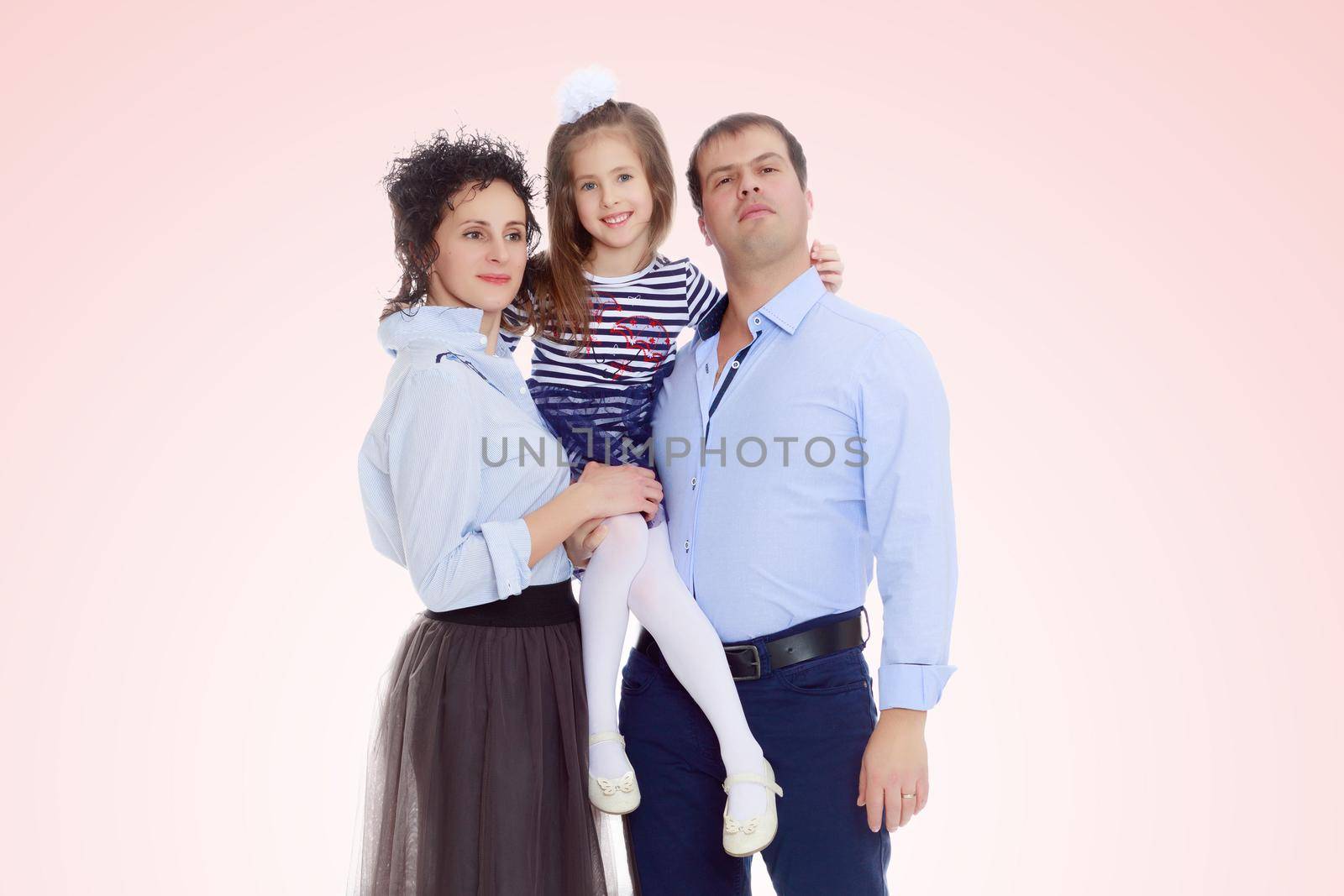 Happy young family, mom dad and little daughter.Parents keep the girl in her arms , and she hugs their neck.Pale pink gradient background.