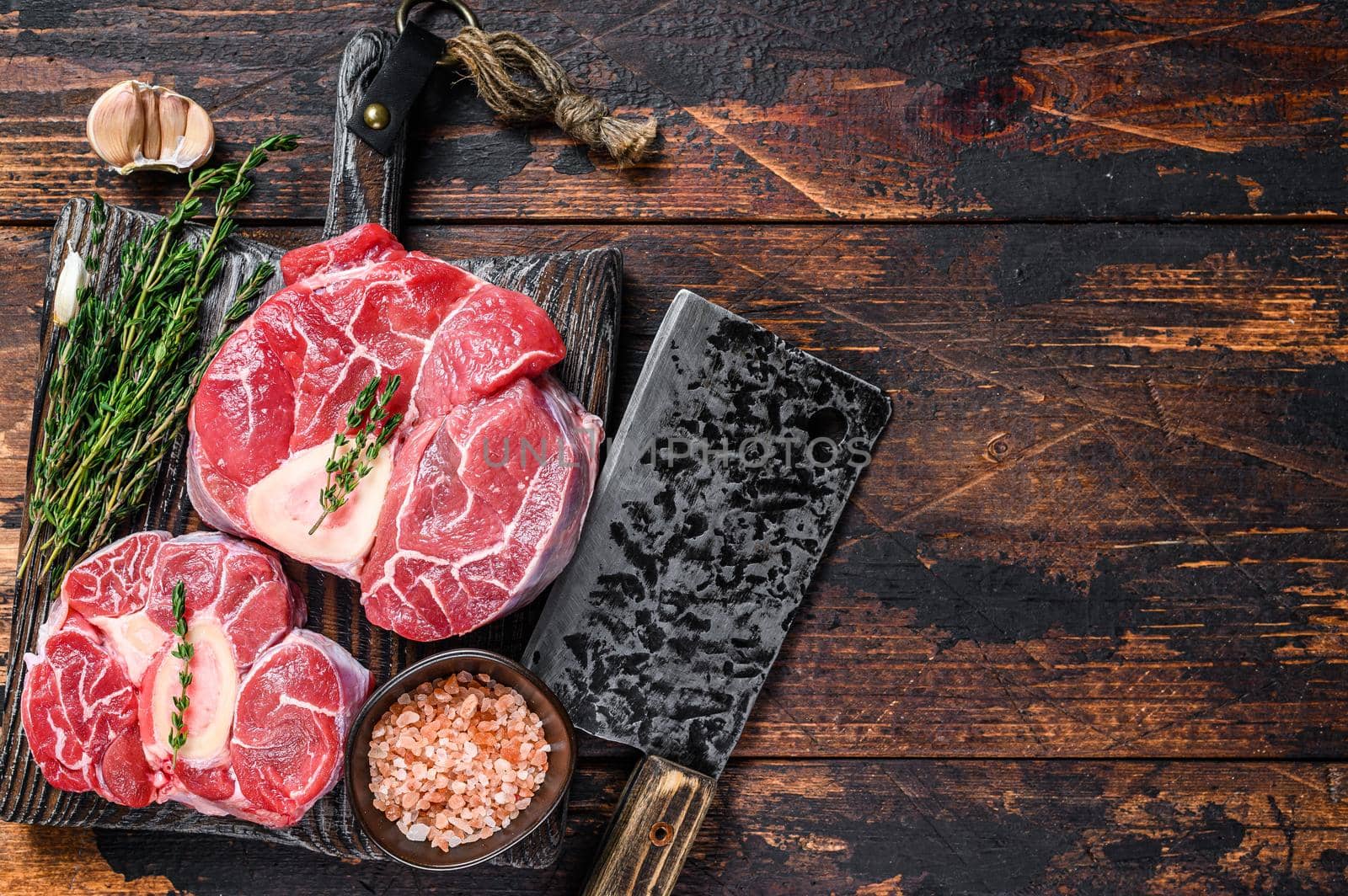 Raw veal shank steak meat osso buco, cooking italian ossobuco. Dark Wooden background. Top view. Copy space.