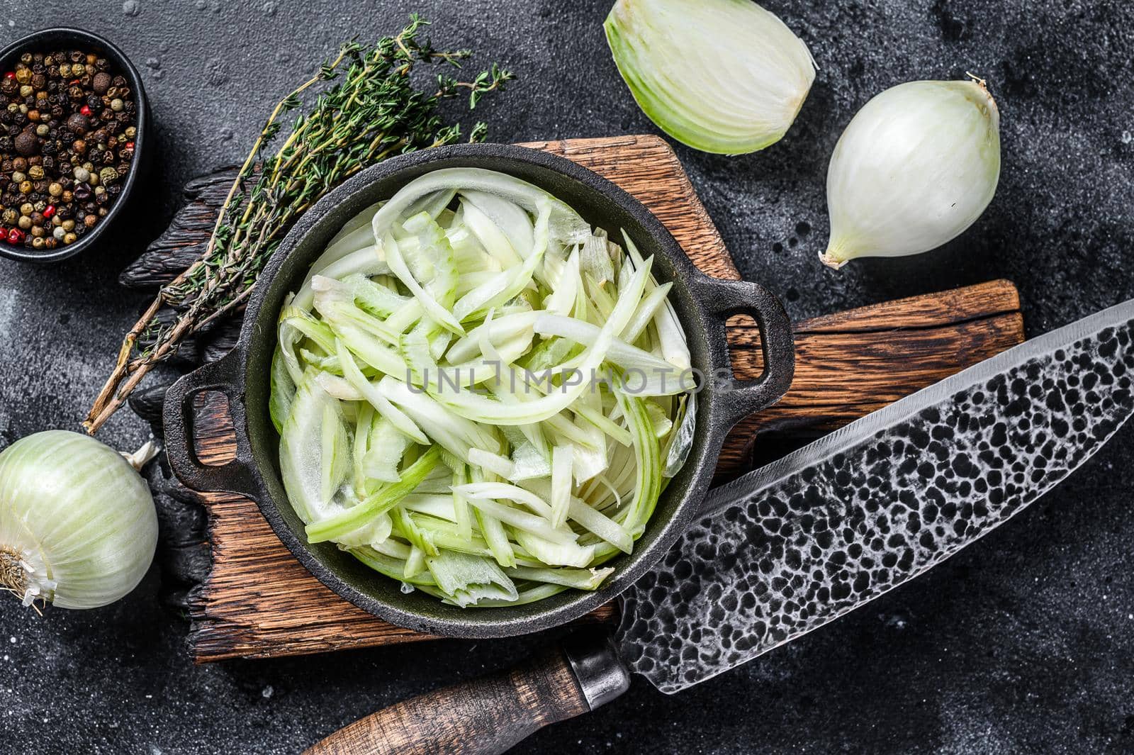 Sliced white onion in a pan. Black background. Top view.