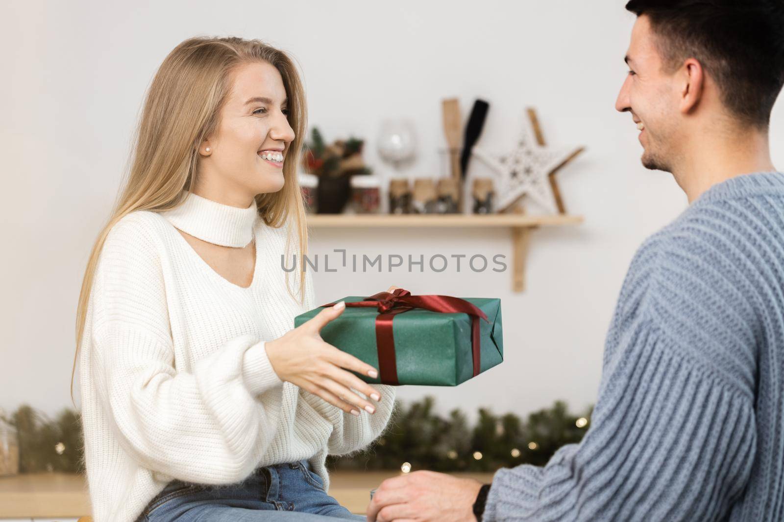 Sweet young couple opening Christmas gifts in the living room at home