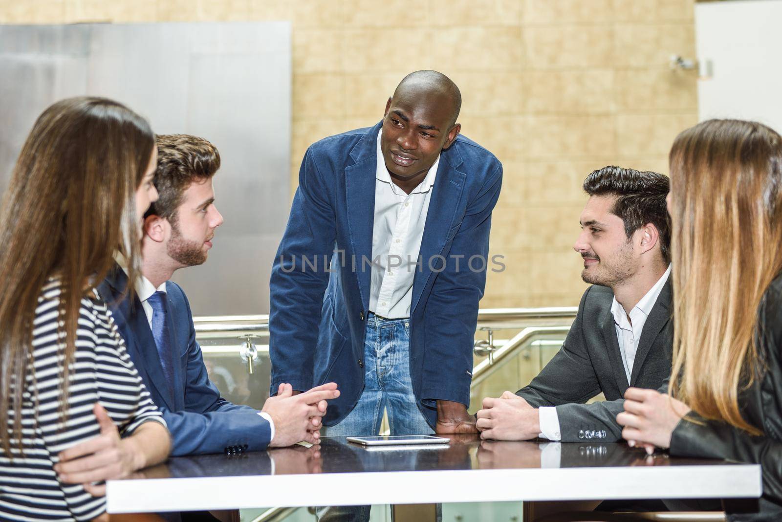Businesspeople, teamwork. Group of multiethnic busy people working in an office with a black businessman as a leader of the group